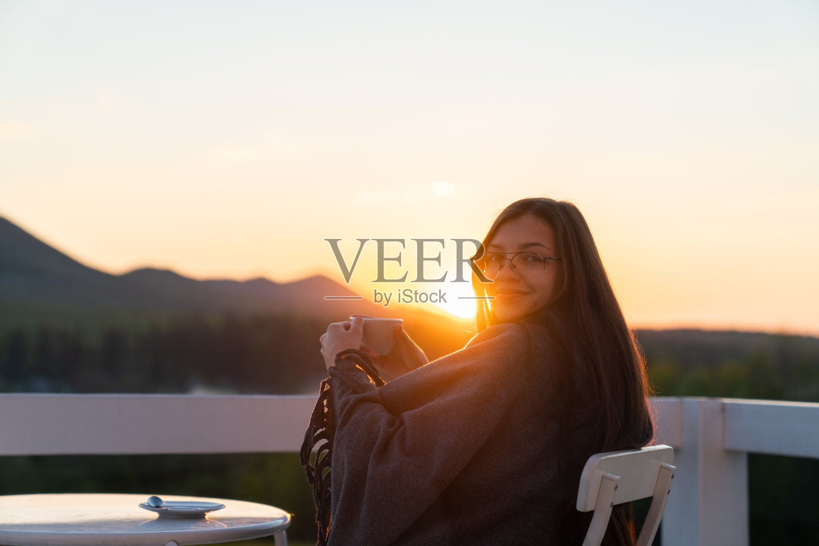 年轻女子在美丽的山景阳台上喝着热咖啡照片摄影图片