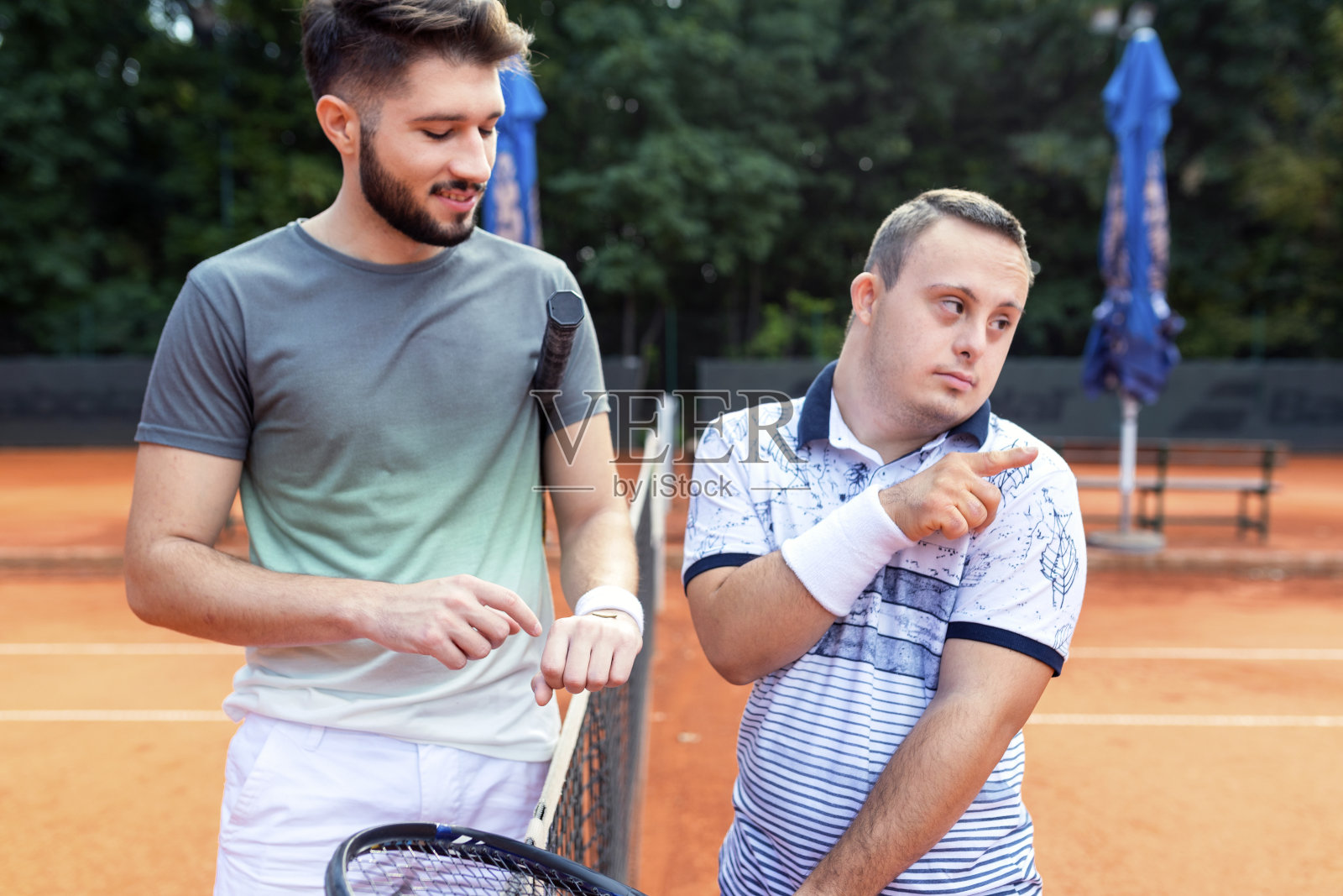 患有唐氏综合征的年轻男子在网球场上照片摄影图片