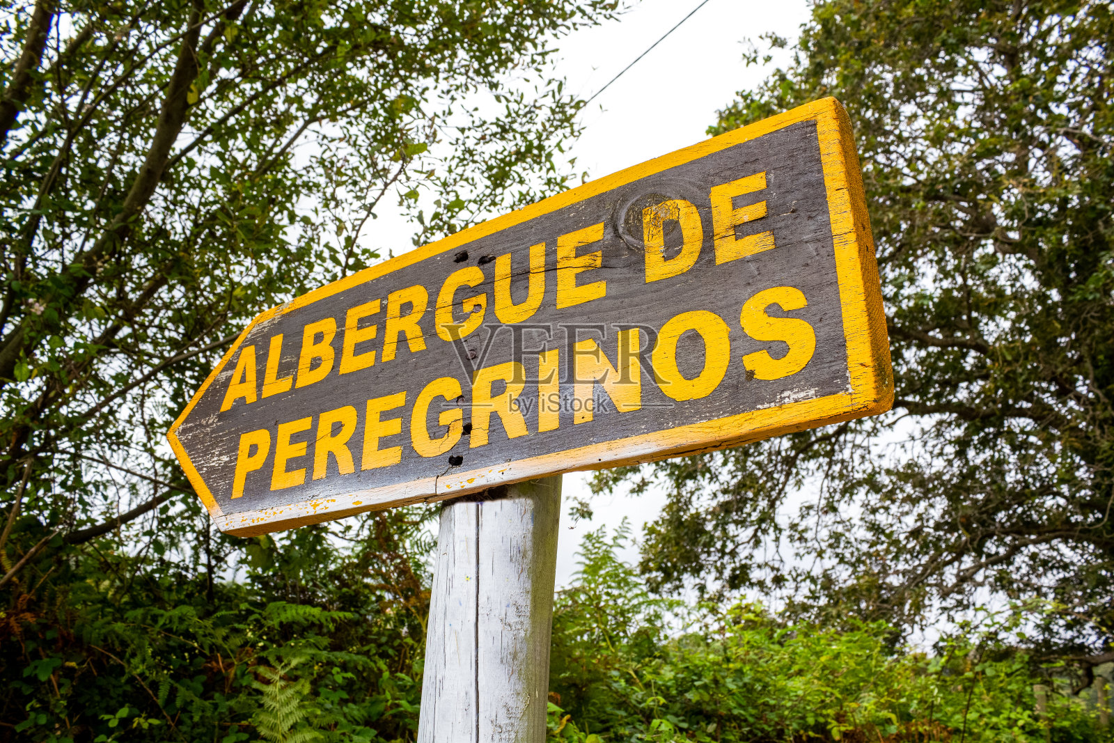 在西班牙，一个警告“朝圣者旅馆”附近的木制标志照片摄影图片