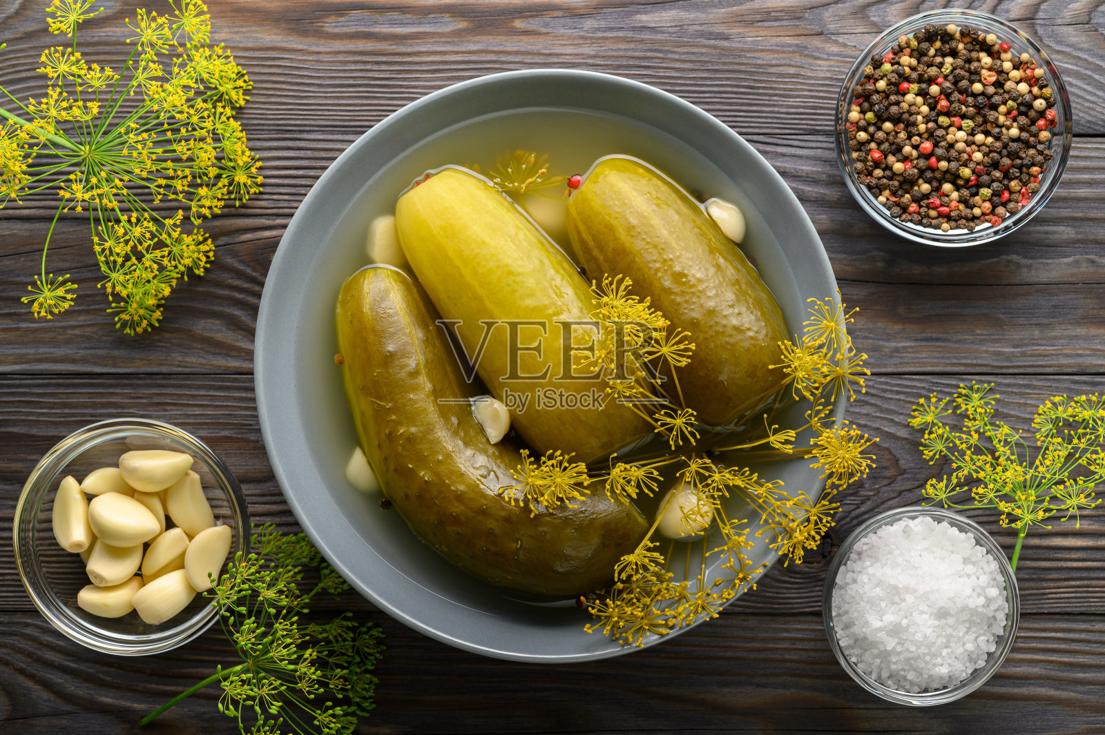 健康的发酵食品。发酵的黄瓜放在一个盘子里，背景是深色的木头。照片摄影图片