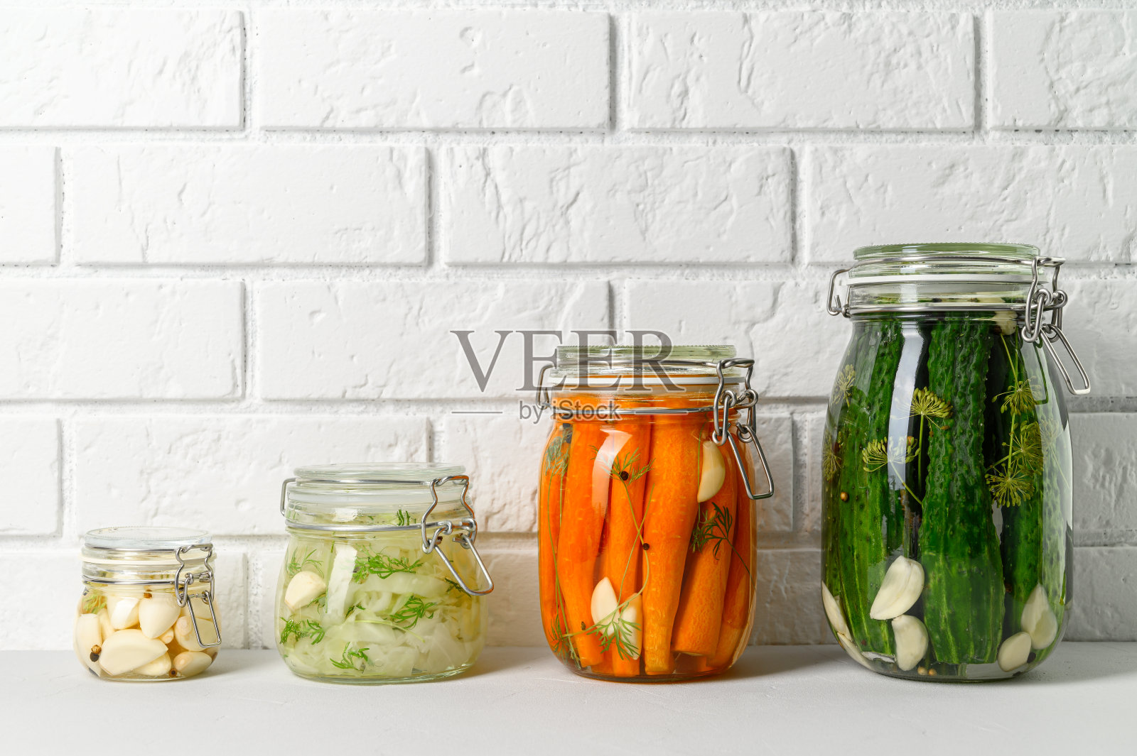 健康的素食。自制发酵蔬菜黄瓜，胡萝卜，卷心菜和大蒜在玻璃罐中。照片摄影图片