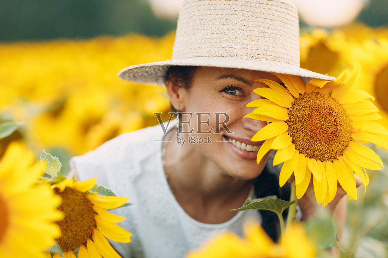 美丽微笑的年轻女子戴着一顶帽子，眼睛上戴着花，脸上戴着向日葵照片摄影图片