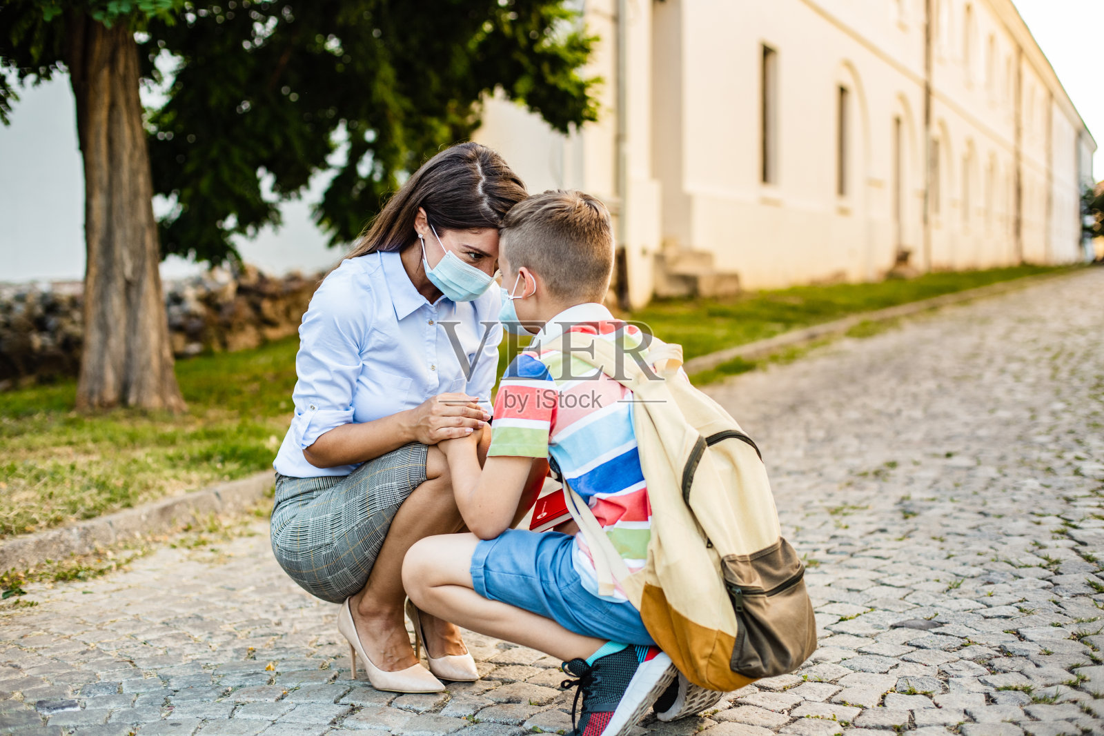母亲和儿子戴着口罩。母亲在儿子上学前鼓励他照片摄影图片