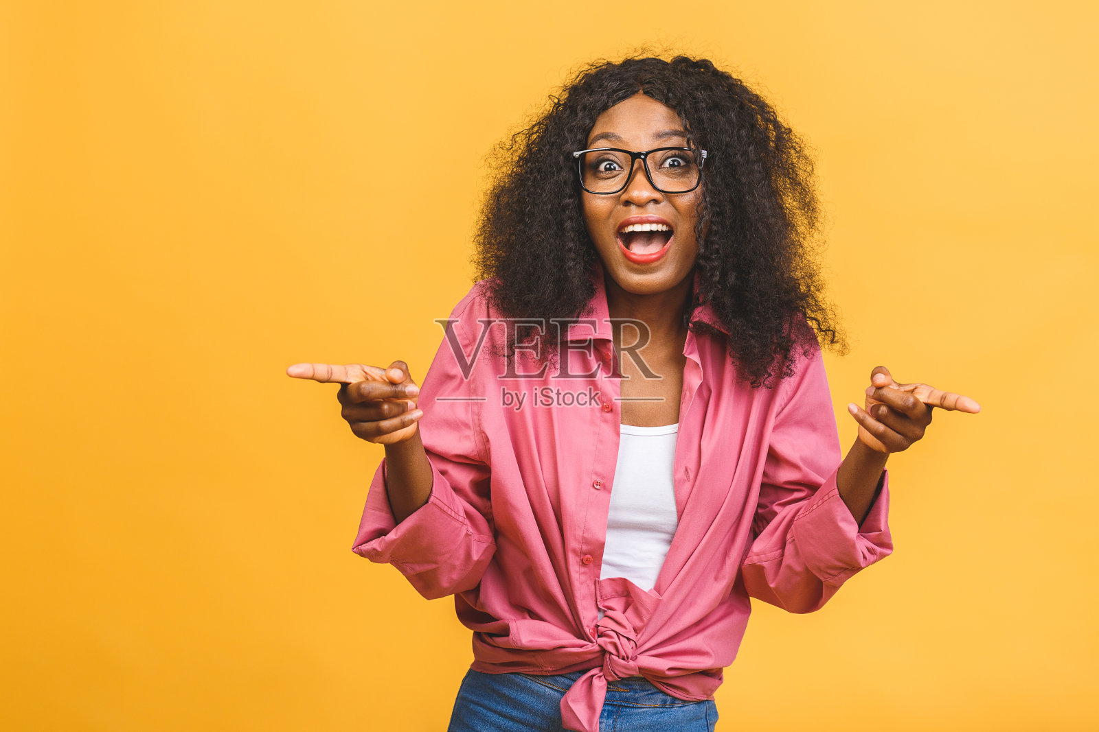 欢乐的年轻非洲裔美国女人的肖像与卷发摆姿势在工作室与快乐的微笑。皮肤黝黑的女人开心地笑着。孤立在黄色背景上。照片摄影图片