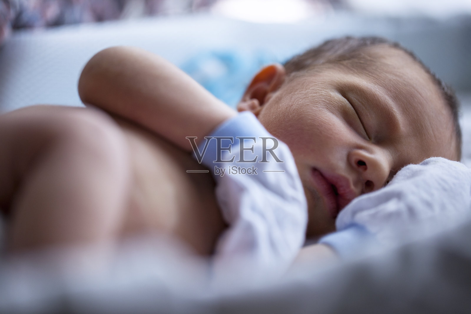 赤膊男婴戴着白手套睡在婴儿床里照片摄影图片