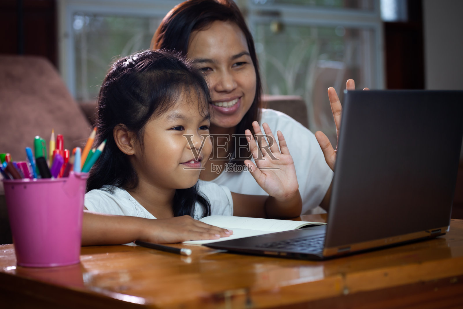 亚洲女童用笔记本学习在线技术，旁边有她妈妈的建议。照片摄影图片