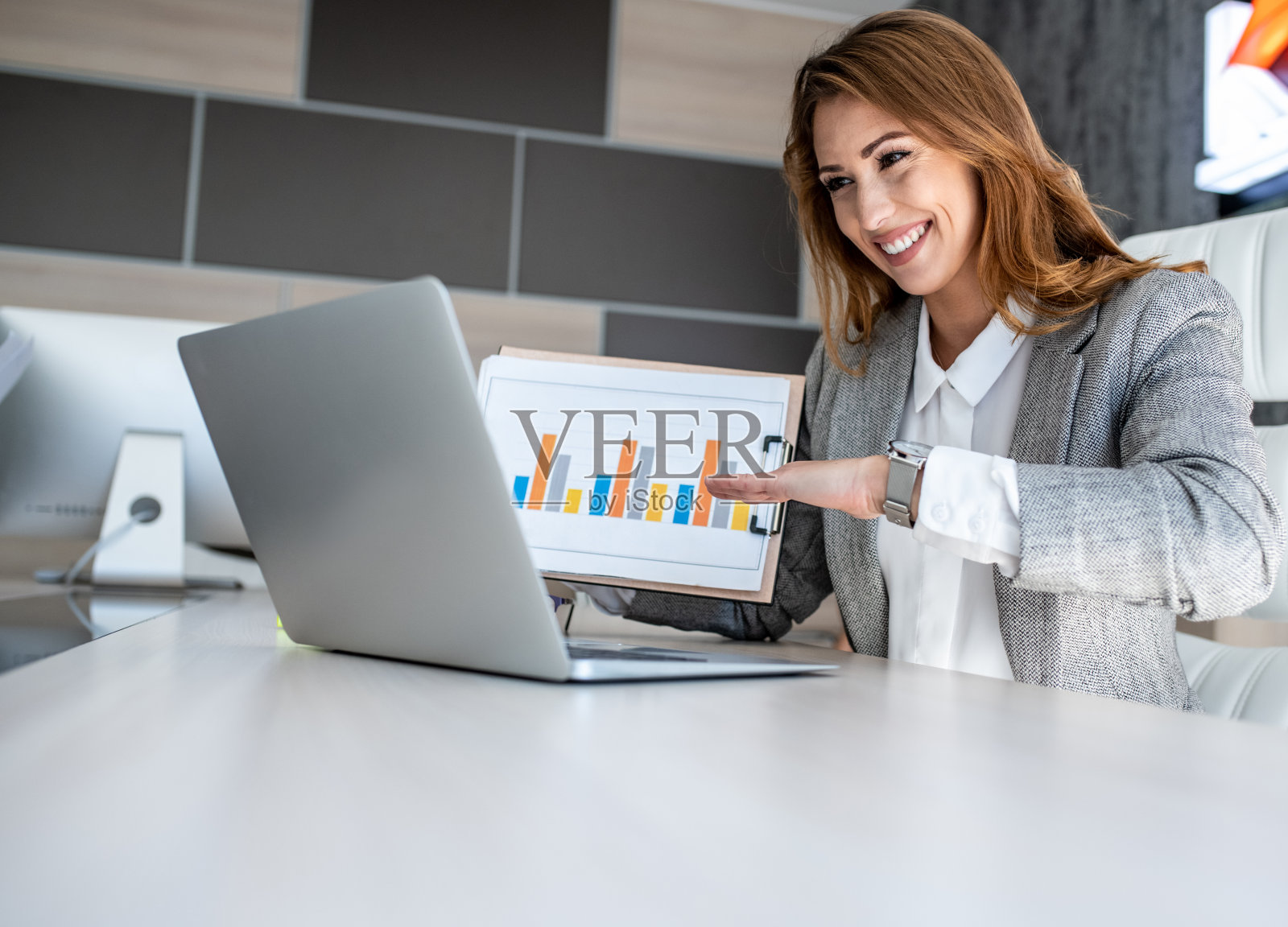 一位商业女性坐在办公室的办公桌前，参加一个在线会议并显示商业数据照片摄影图片