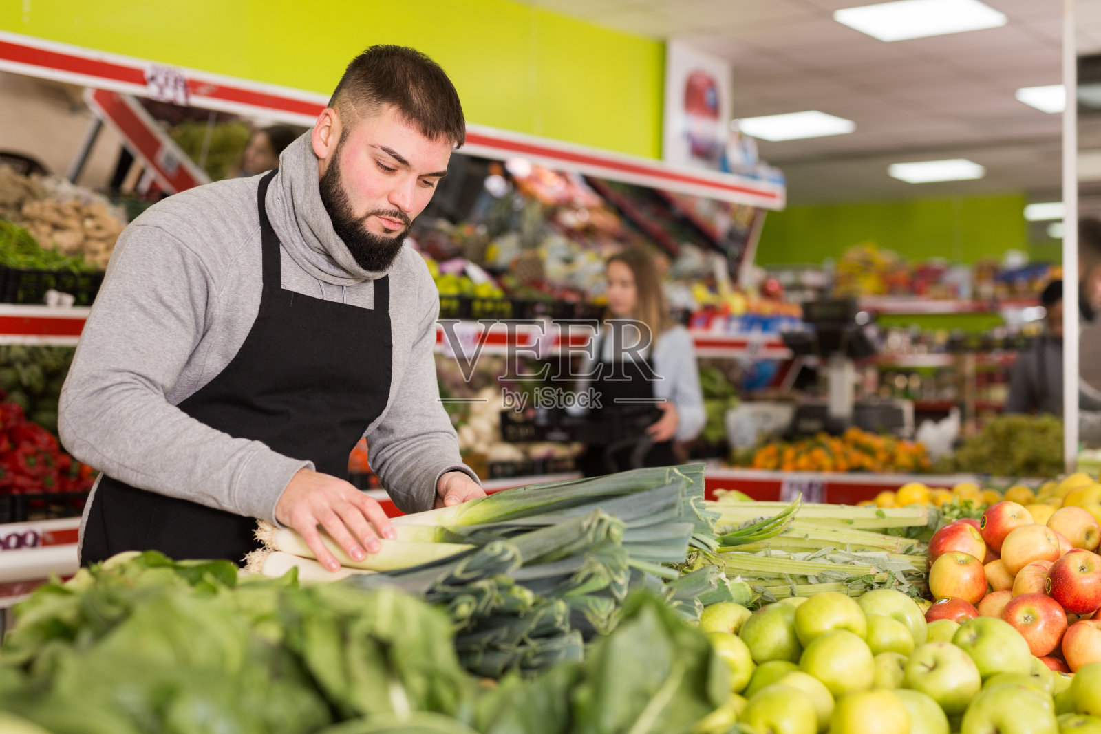 男店员在杂货店的柜台上放新鲜的韭菜照片摄影图片
