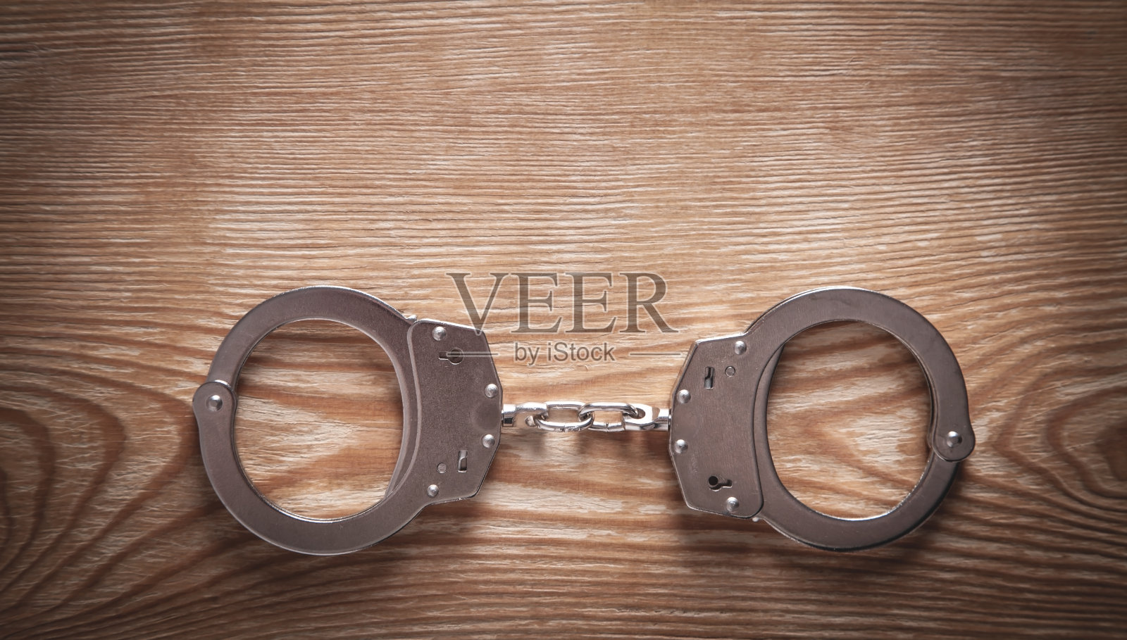 木制背景上的金属手铐。照片摄影图片