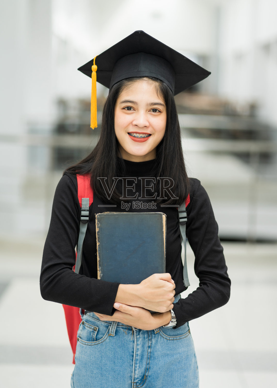 女青少年大学生的肖像，拿着书，背着书包，戴着毕业帽，代表了毕业的概念照片摄影图片