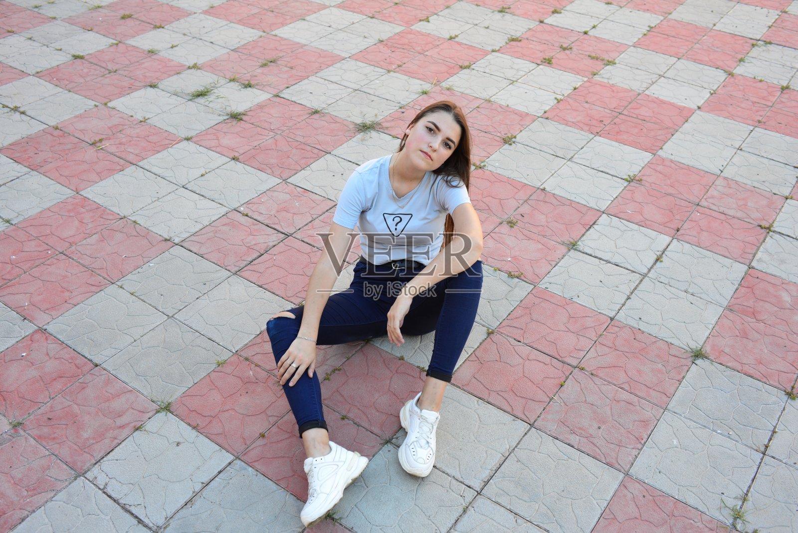 年轻活泼的时髦年轻女子坐在乡间的路上，穿着时髦的夏装。袋里。晚上温暖的颜色。日落。照片摄影图片