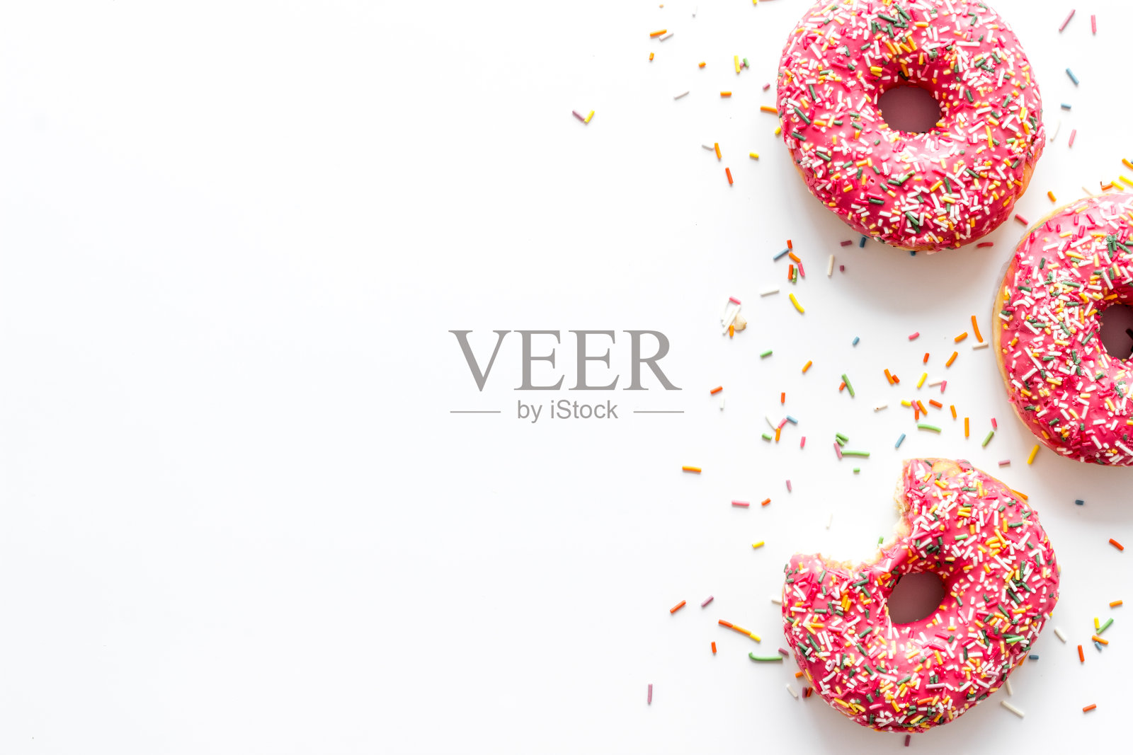 粉红色的浆果甜甜圈平躺着，俯视图。上釉和撒糖的甜甜圈照片摄影图片