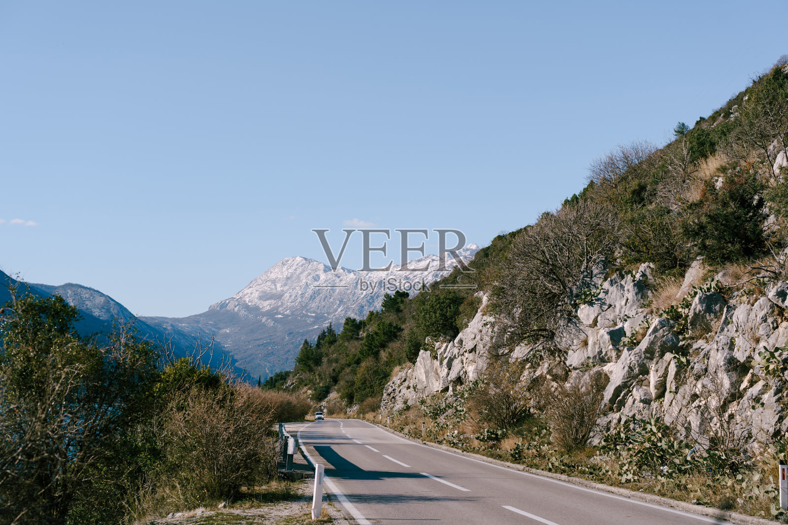 山路蜿蜒，有一辆汽车在相反的方向行驶，俯瞰群山和蓝天。照片摄影图片