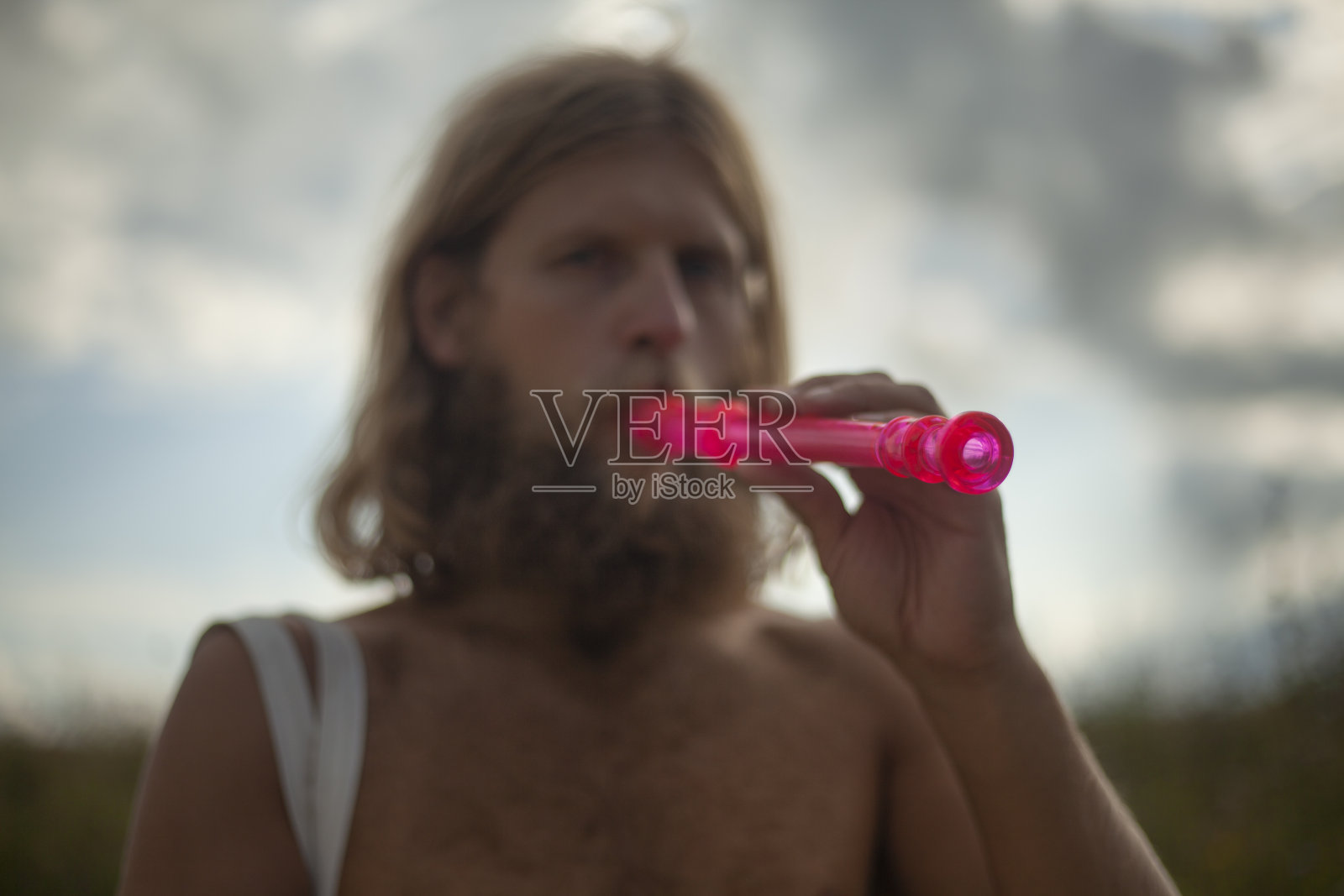 旅行者吹长笛。一个大胡子的家伙。这个人在大自然中旅行。照片摄影图片