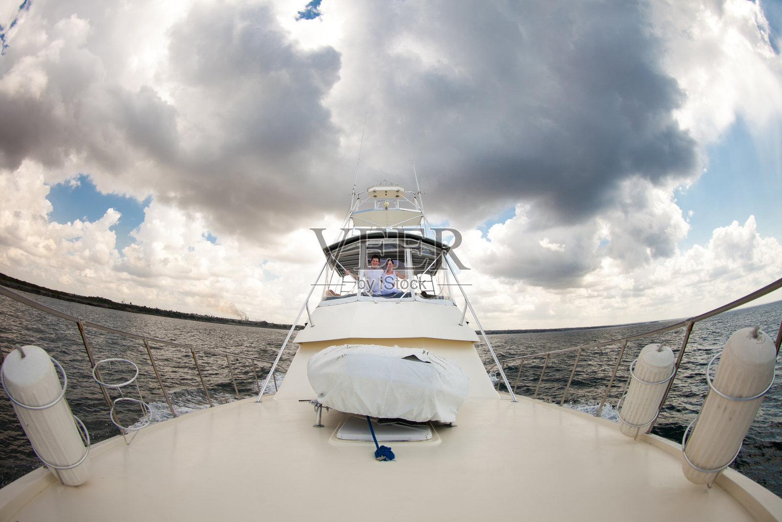 新娘和新郎穿着白色的衣服在游艇上旅行。照片摄影图片