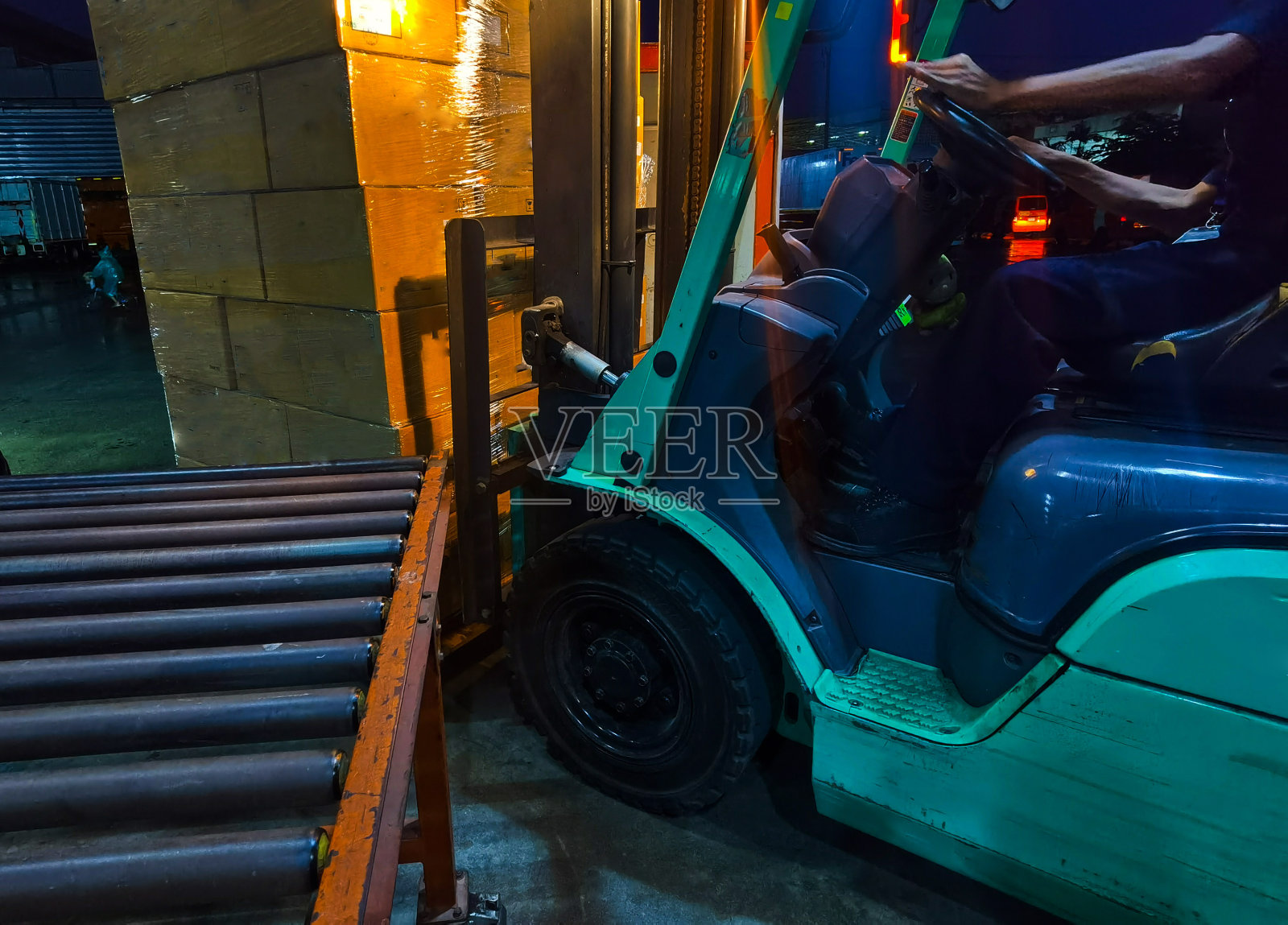在物流运输行业，工人驾驶叉车从集装箱卡车上装载和卸载装运纸箱和木制托盘上的货物到仓库的货物存储照片摄影图片