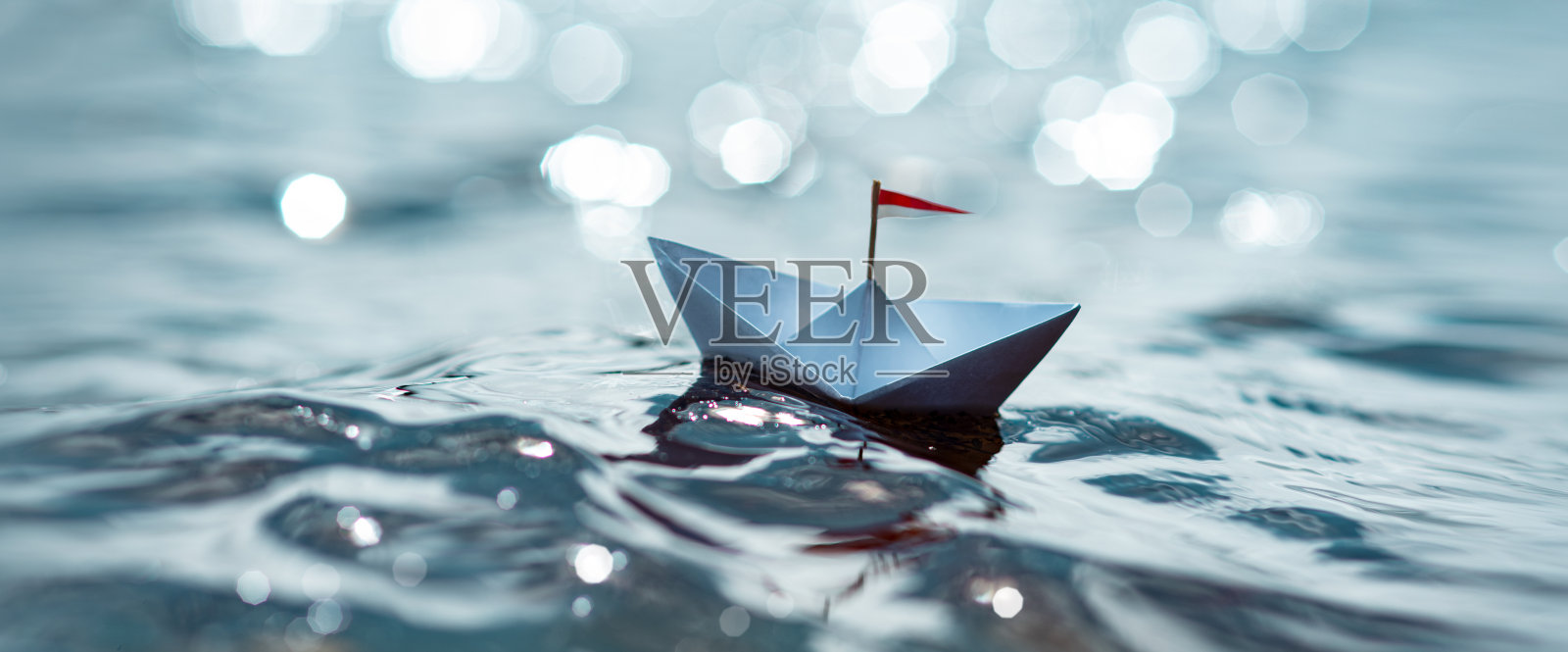 纸船在阳光明媚的海面上航行照片摄影图片