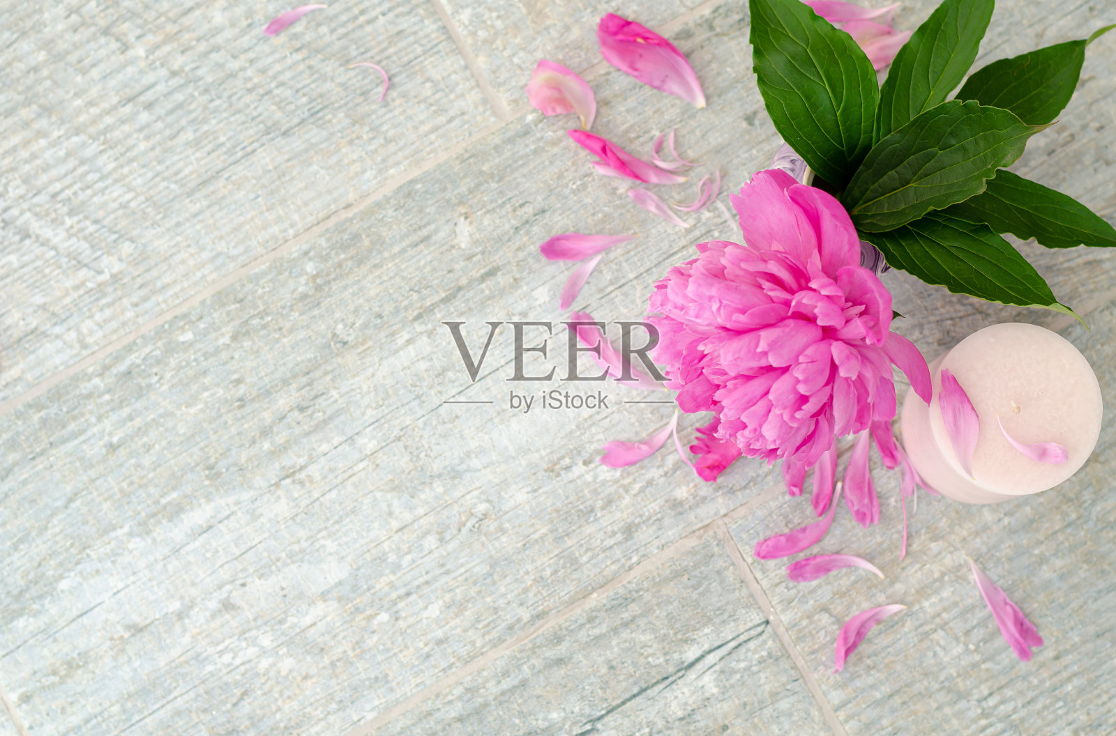 美丽的粉红色牡丹花和白色的蜡烛在灰色的石头背景与复制空间的文字，俯视图。贺卡。照片摄影图片