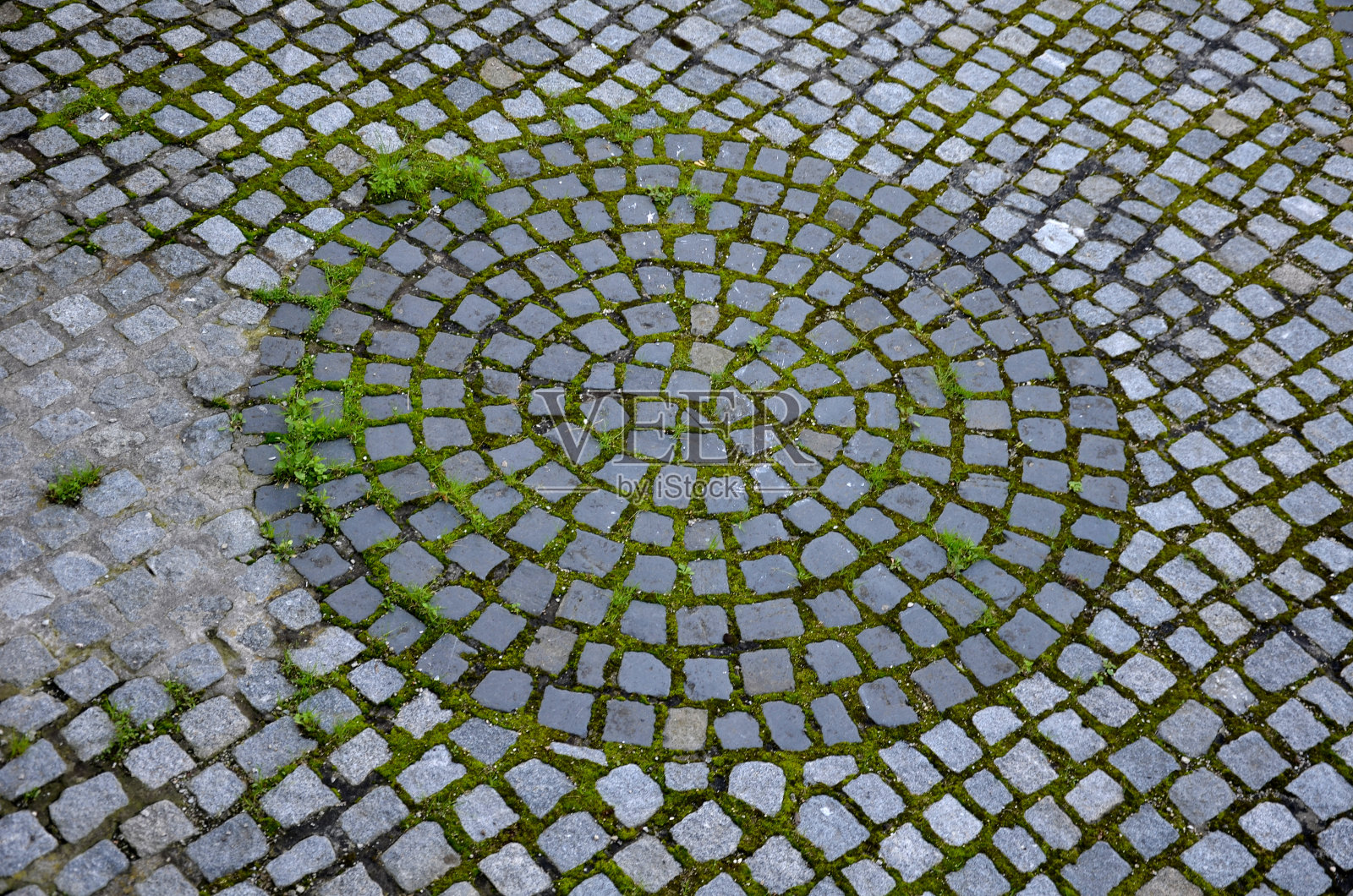铺满鹅卵石的石头，一圈长满青草的灰色老立方体照片摄影图片