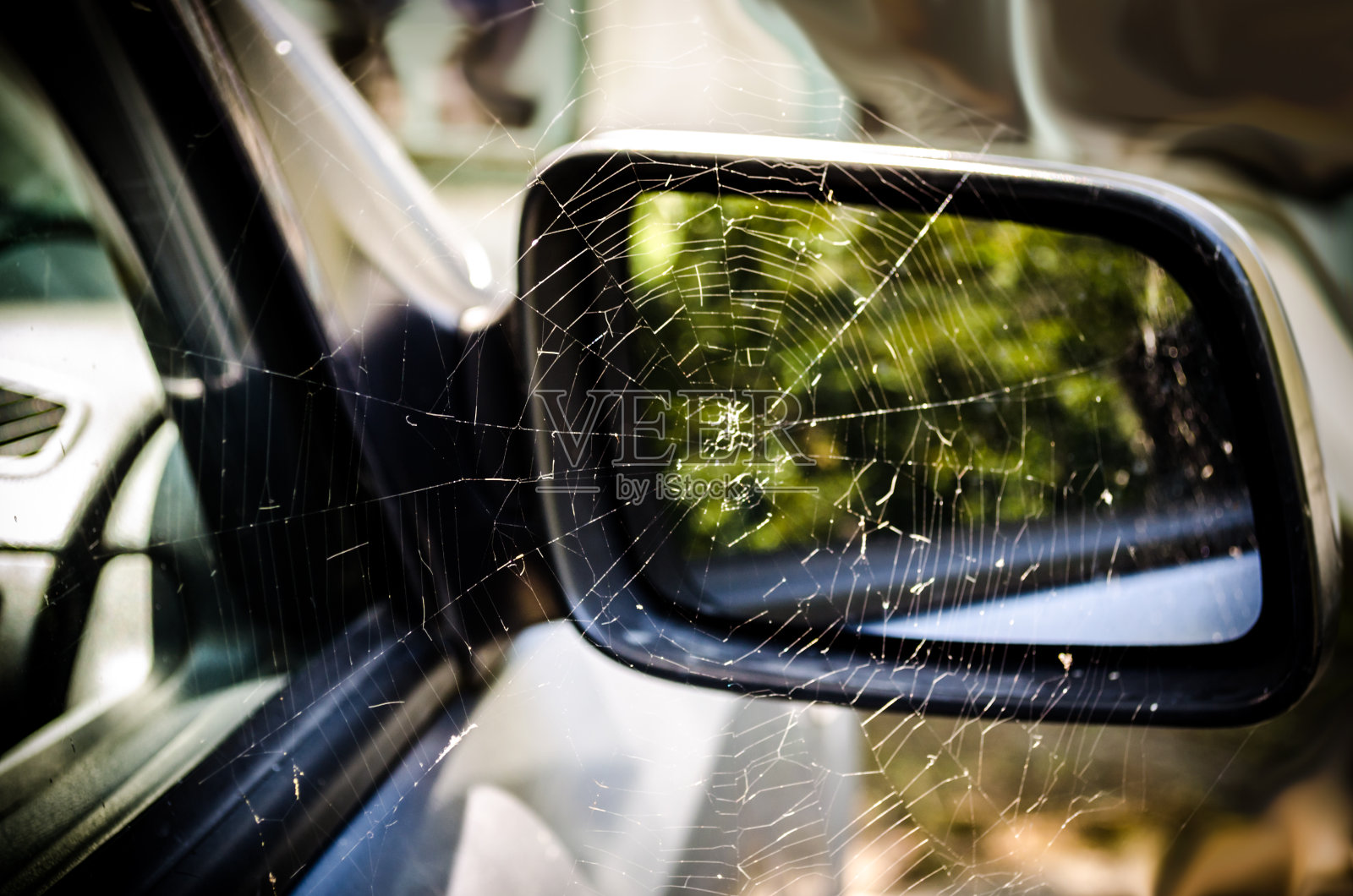 一辆废弃的旧车后视镜上的蜘蛛网。回收旧汽车的概念。照片摄影图片