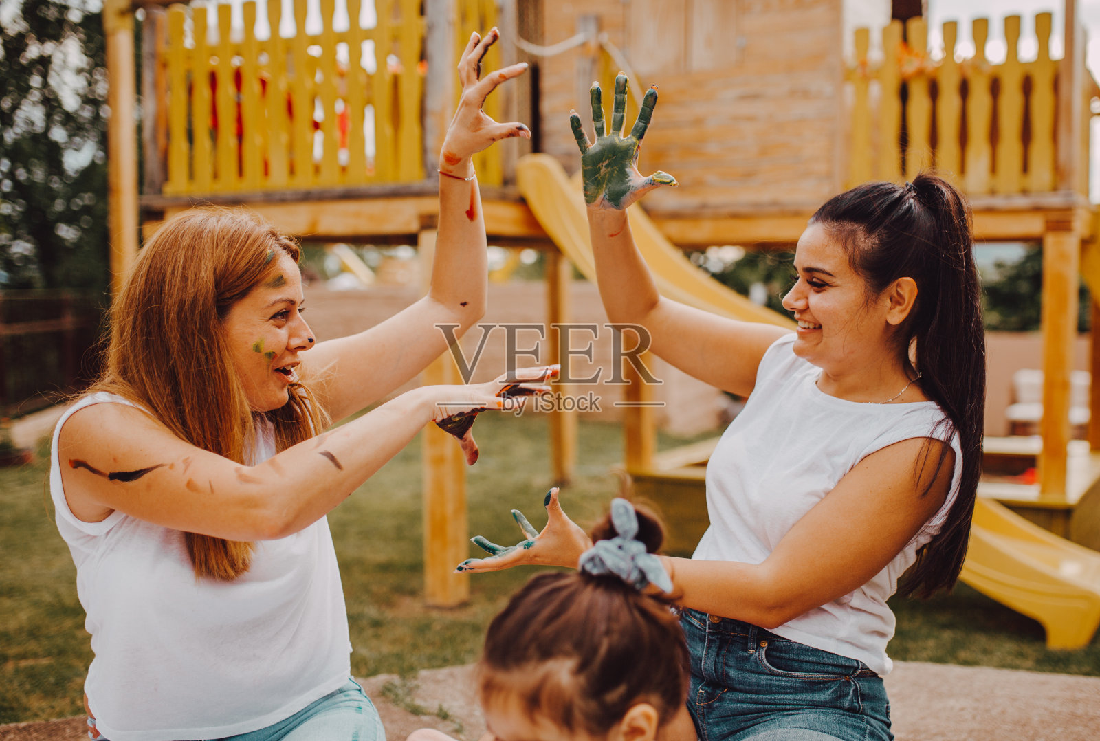 两个有趣的姐妹玩和愚弄他们的手浸在彩色油漆照片摄影图片