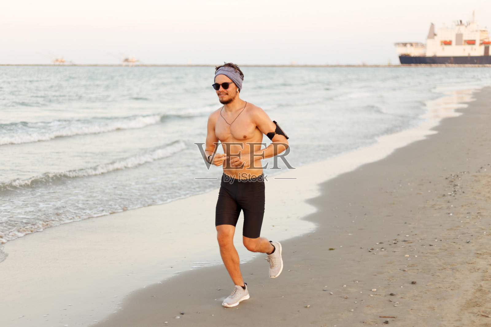 在沙滩上训练跑步者。适合夏季进行全身锻炼的年轻男性运动健身模式。照片摄影图片