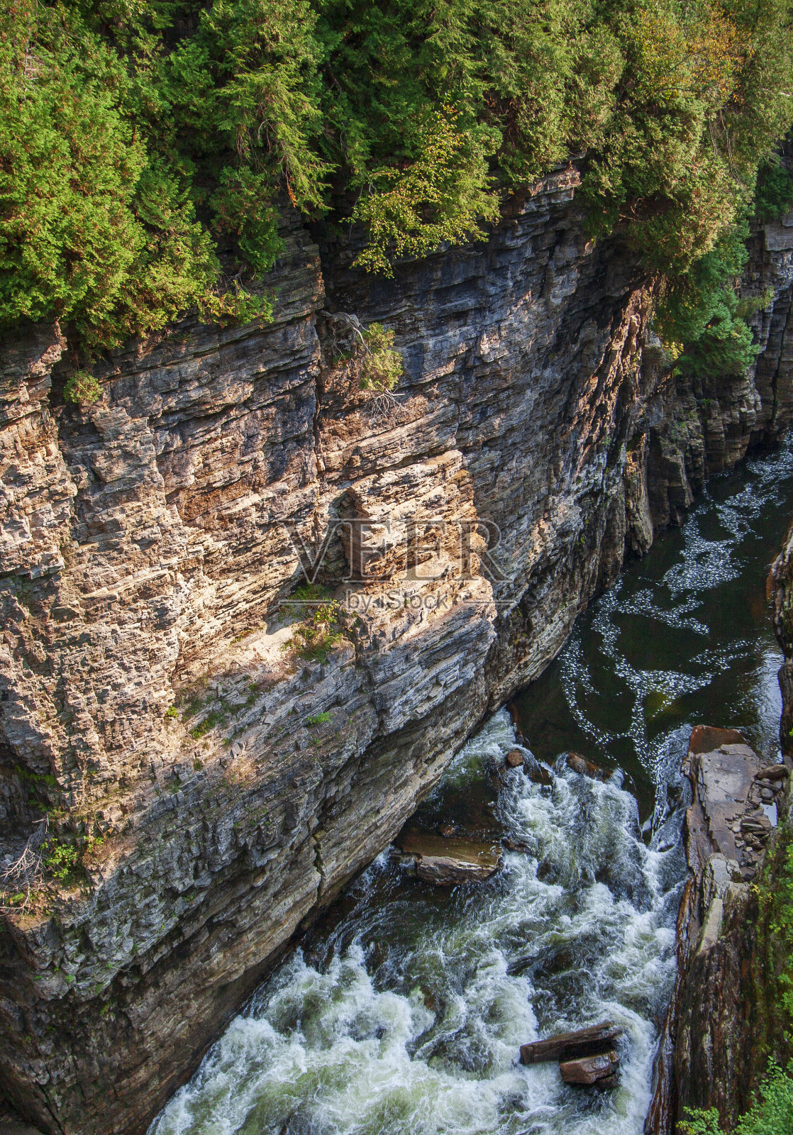 河流穿过深深的峡谷，露出许多沉积岩地层照片摄影图片