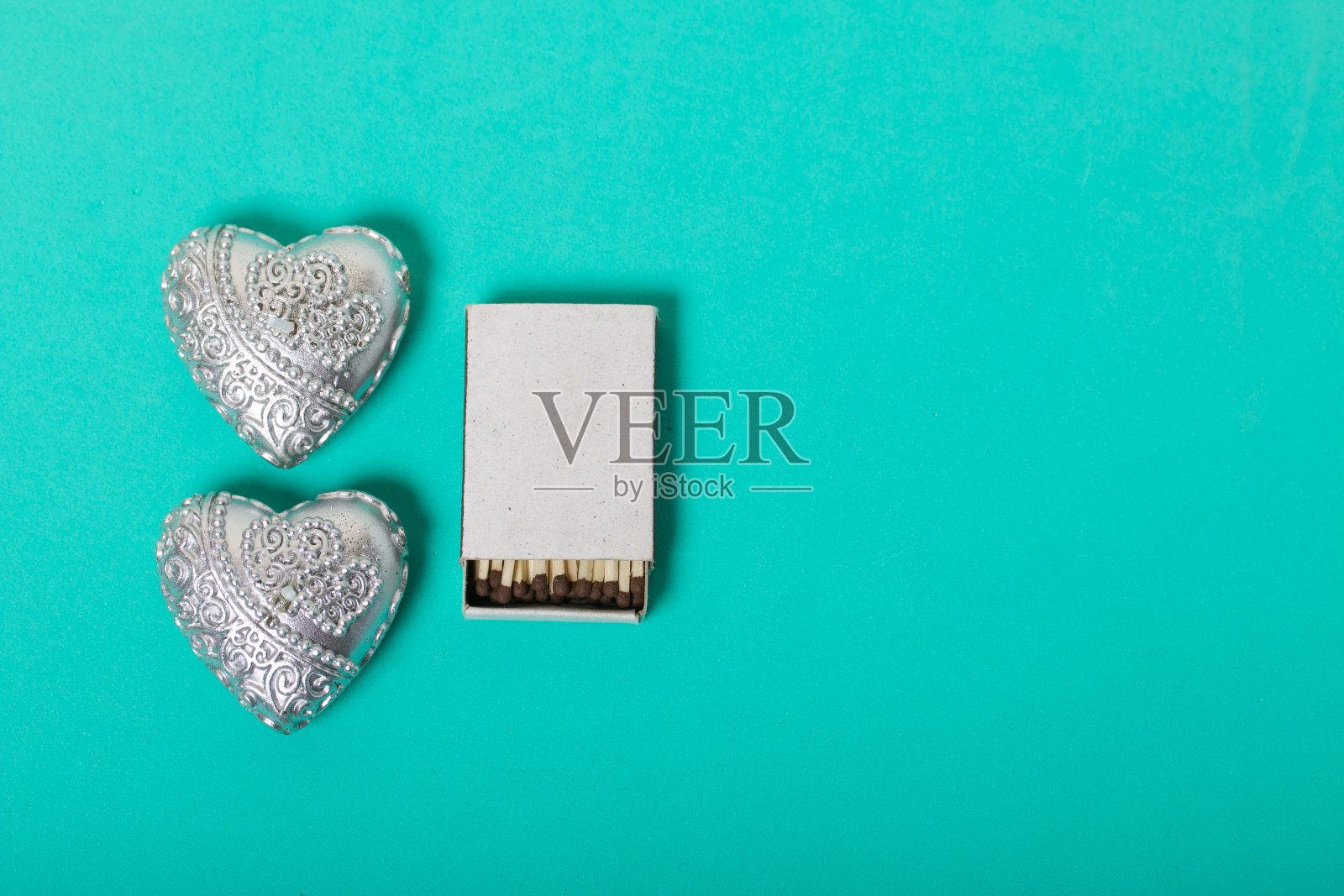 两根心形的装饰蜡烛。在他们旁边是一盒火柴。爱和相聚的对象。在一个薄荷背景。照片摄影图片