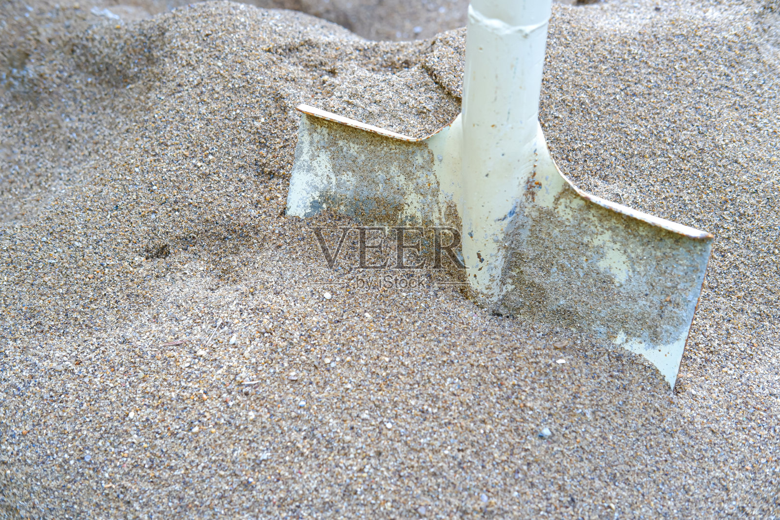 在工地用钢铲铲沙子。照片摄影图片