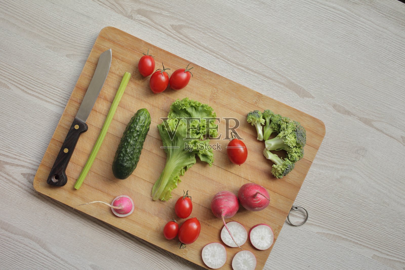 菜板上放着新鲜的蔬菜，放在一个轻木桌上照片摄影图片