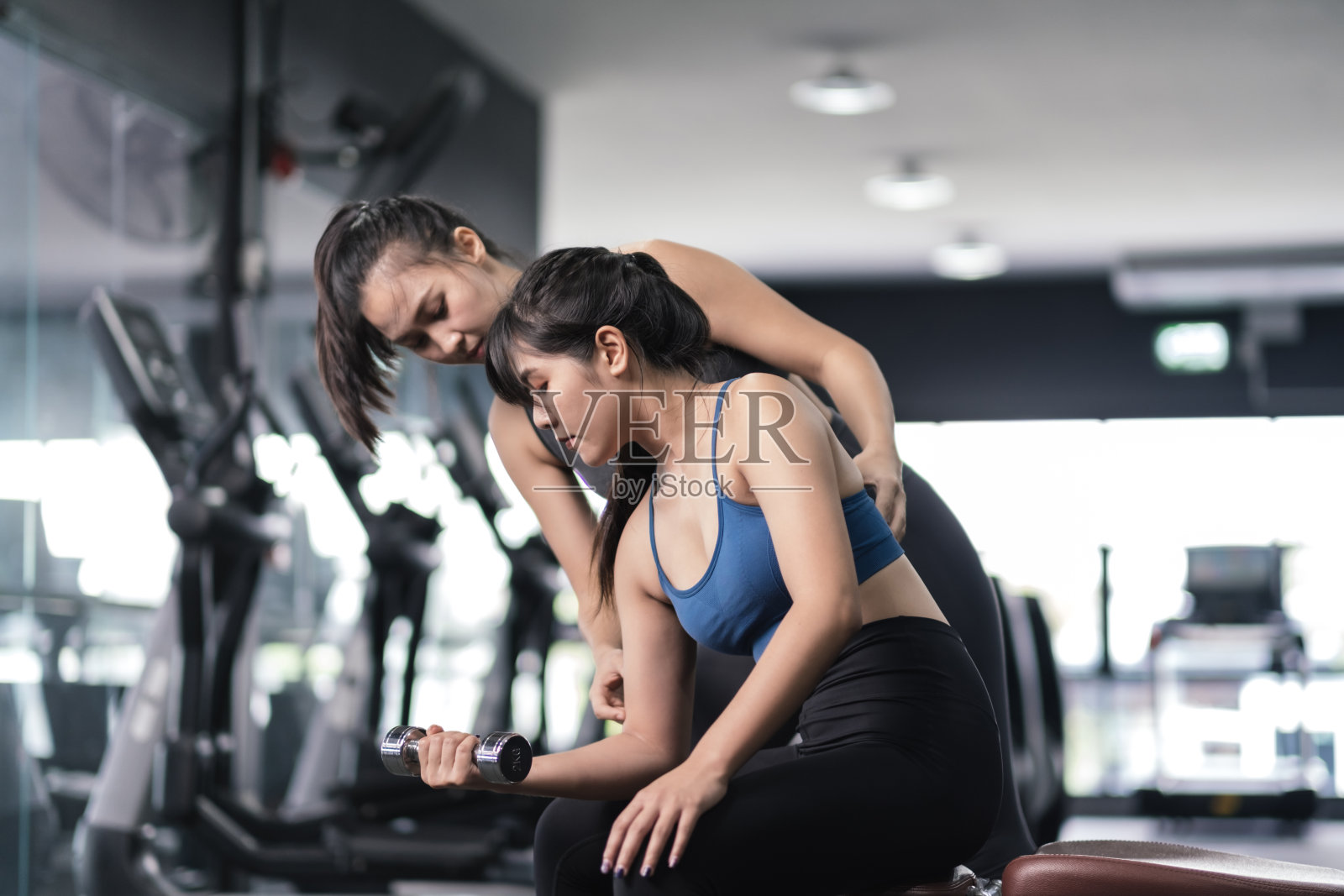 用哑铃训练女性健美者，在健身馆穿着运动服，配有私人教练指导，运动健康健美肌肉，运动员生活理念。照片摄影图片