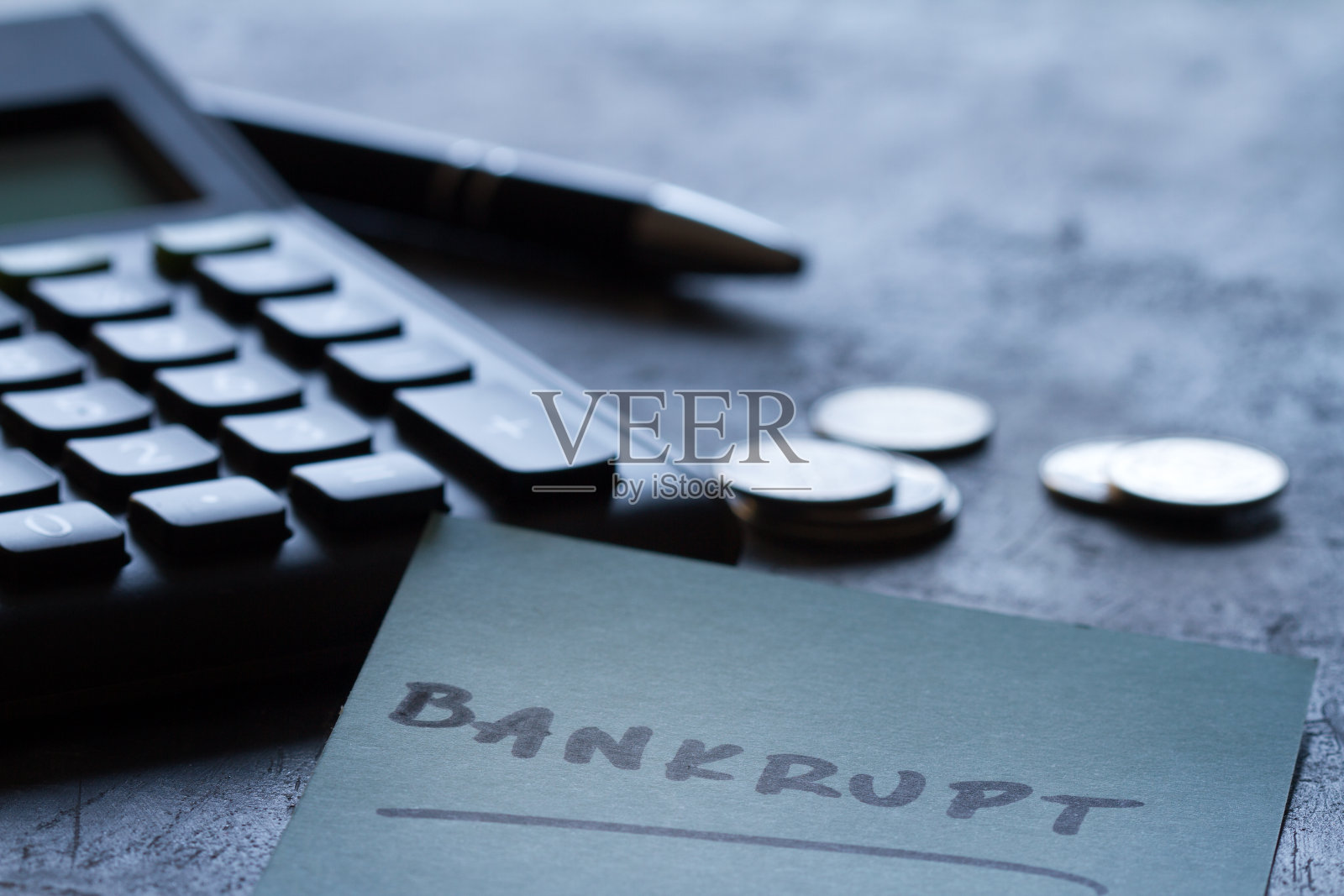 财务失败，破产的概念。硬币，计算器，钢笔和铭文在黑暗的背景破产照片摄影图片