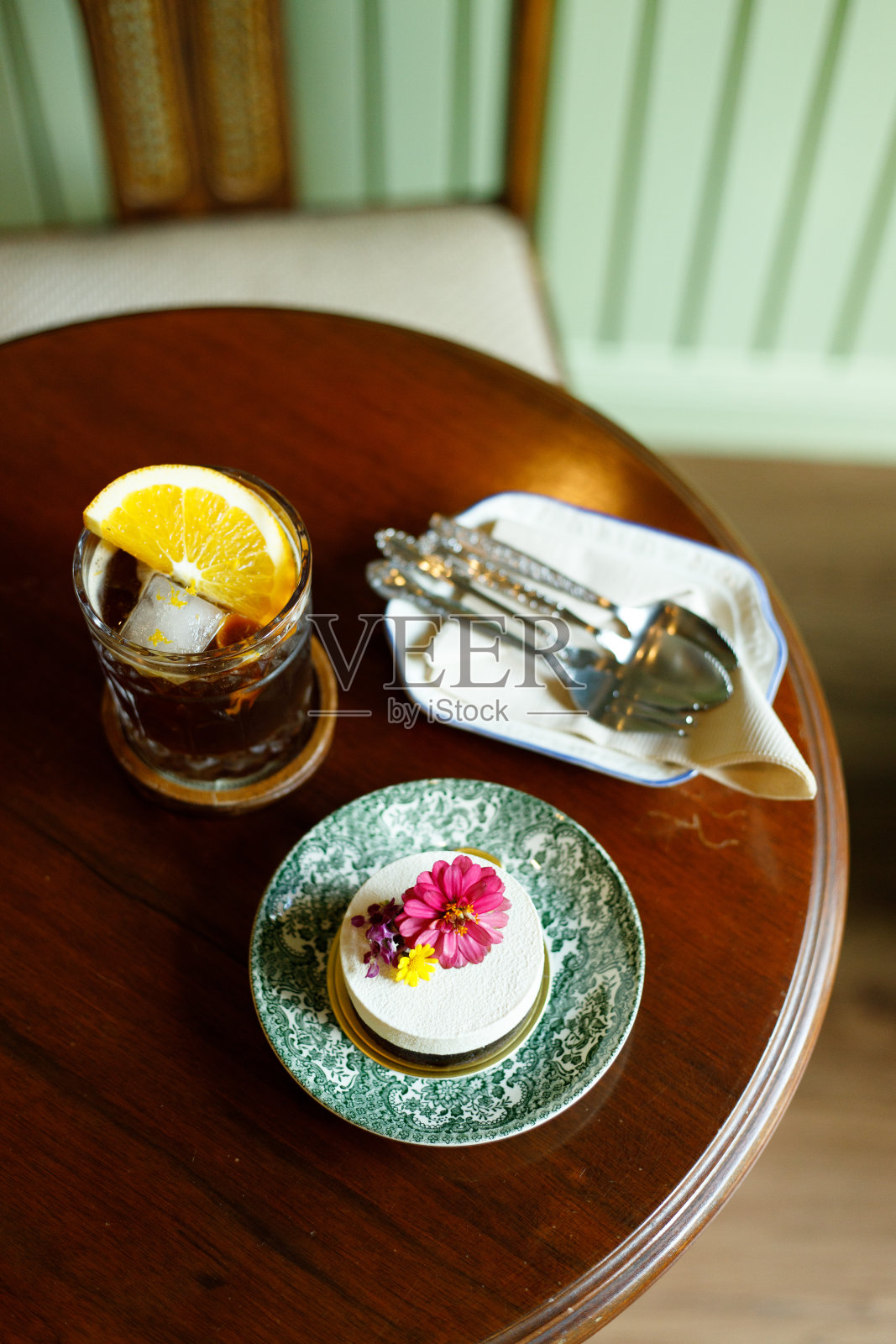 木桌上放着一块蛋糕，上面有可食用的花和冰咖啡照片摄影图片