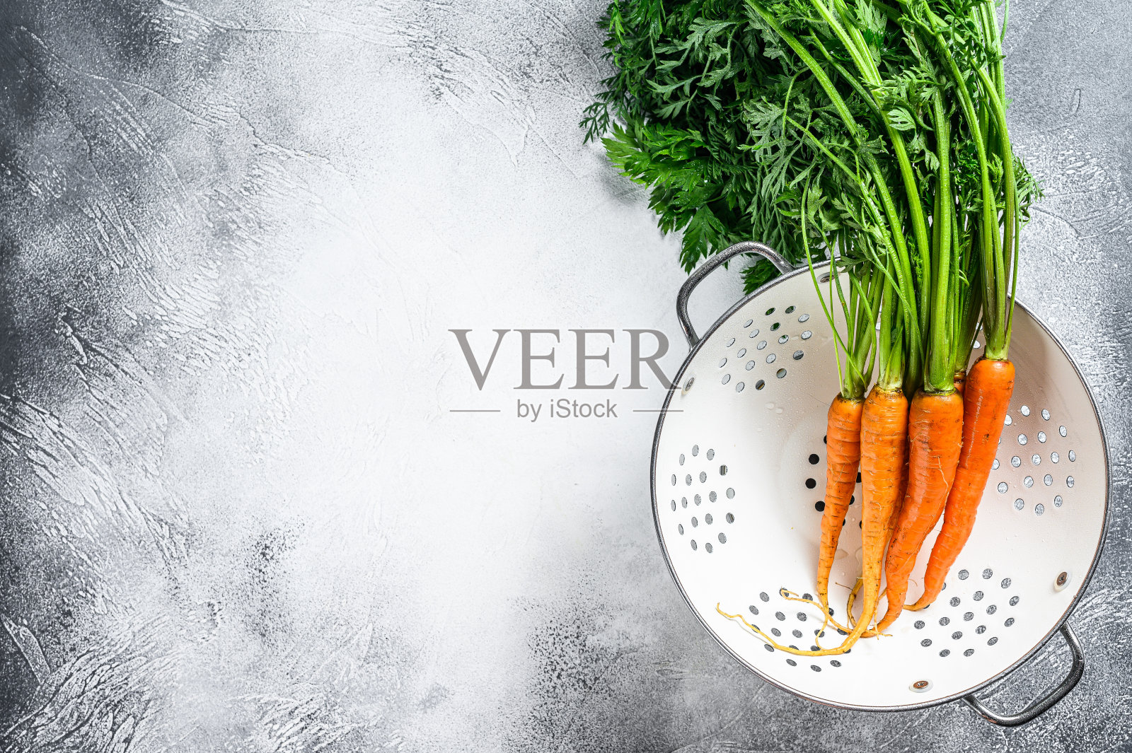 用滤锅洗过的新鲜胡萝卜。灰色的背景。前视图。本空间照片摄影图片