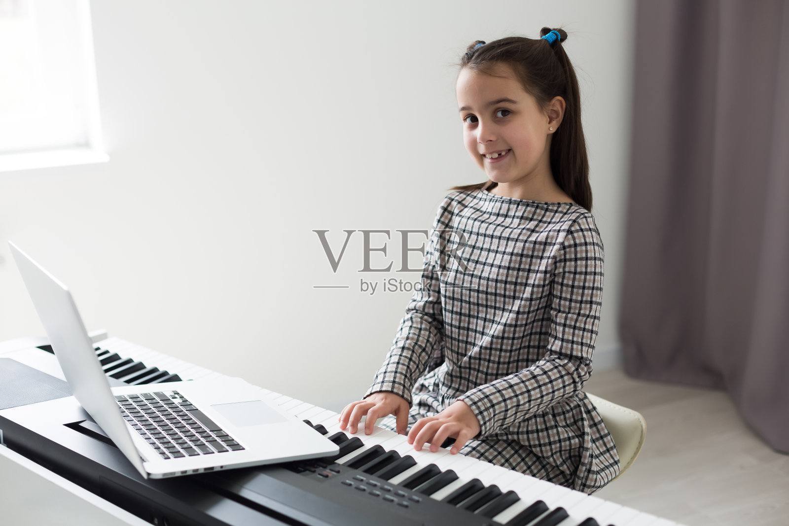 给弹钢琴的女孩上一堂家庭音乐课。隔离期间儿童在家活动的想法。音乐的概念照片摄影图片