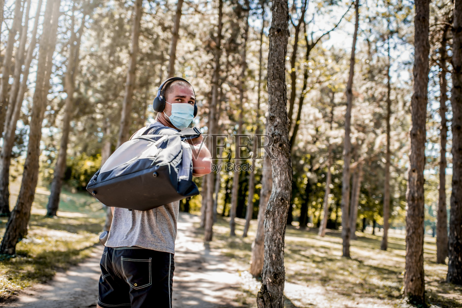 年轻男子在运动服与医疗口罩在他的脸上进行训练。照片摄影图片