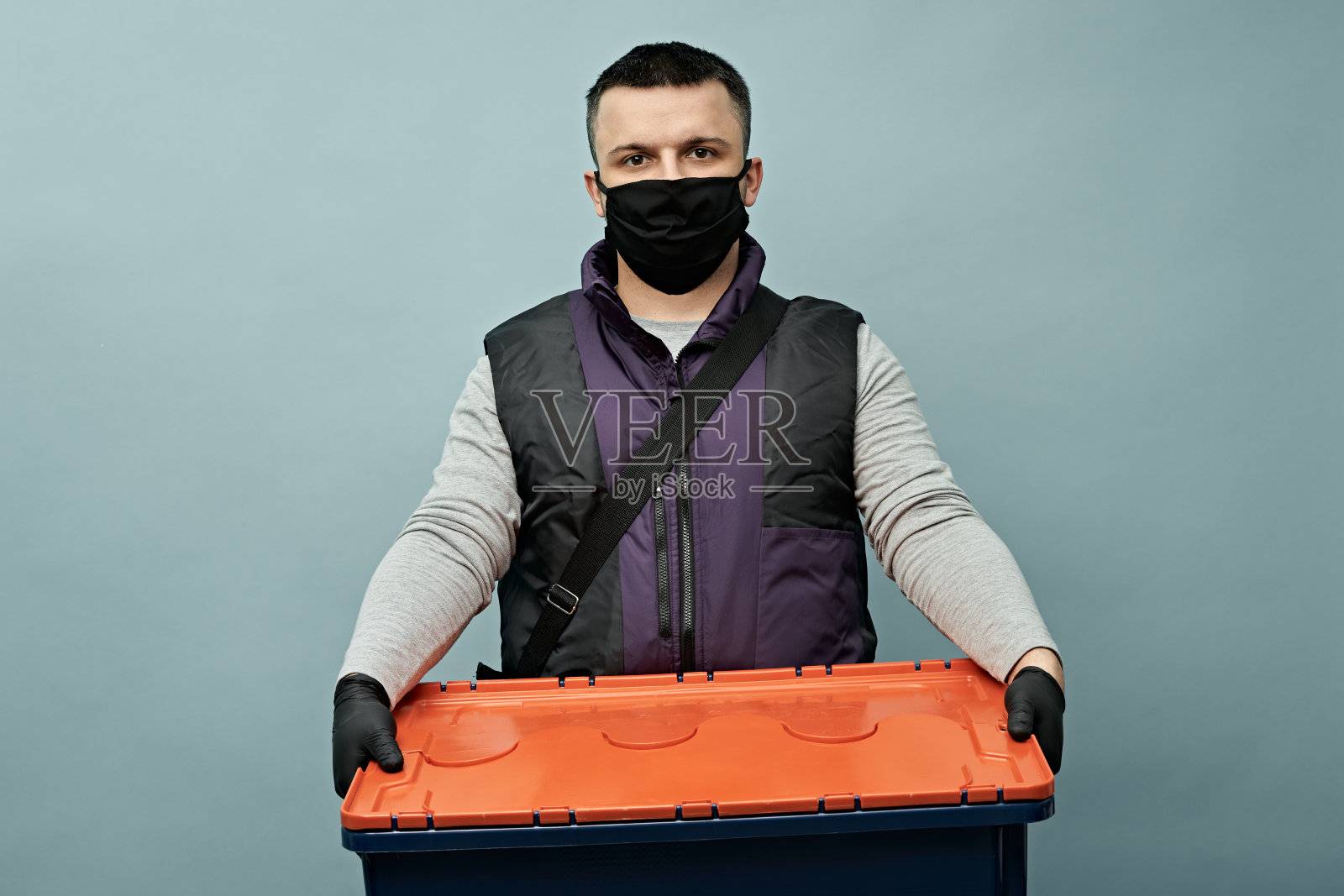 带着防护面具的快递员在递送食物。交付在隔离。大流行。照片摄影图片