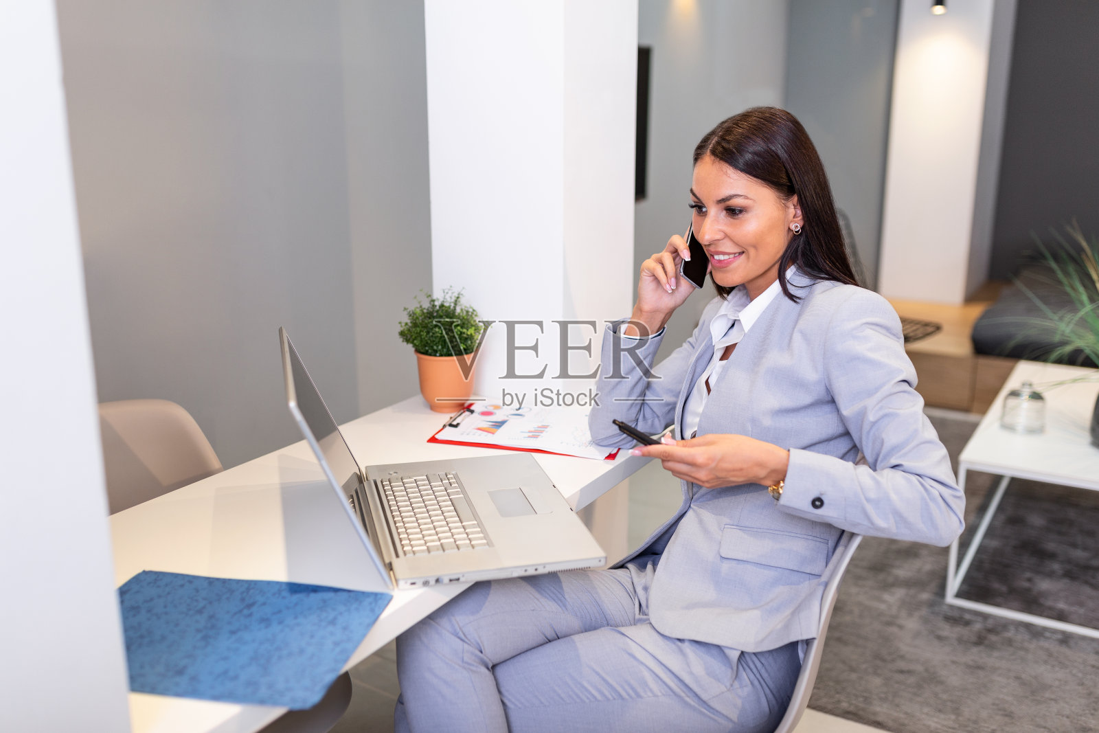 年轻愉快快乐快乐可爱美丽的商业女人坐在办公室里使用笔记本电脑和她的移动电话照片摄影图片