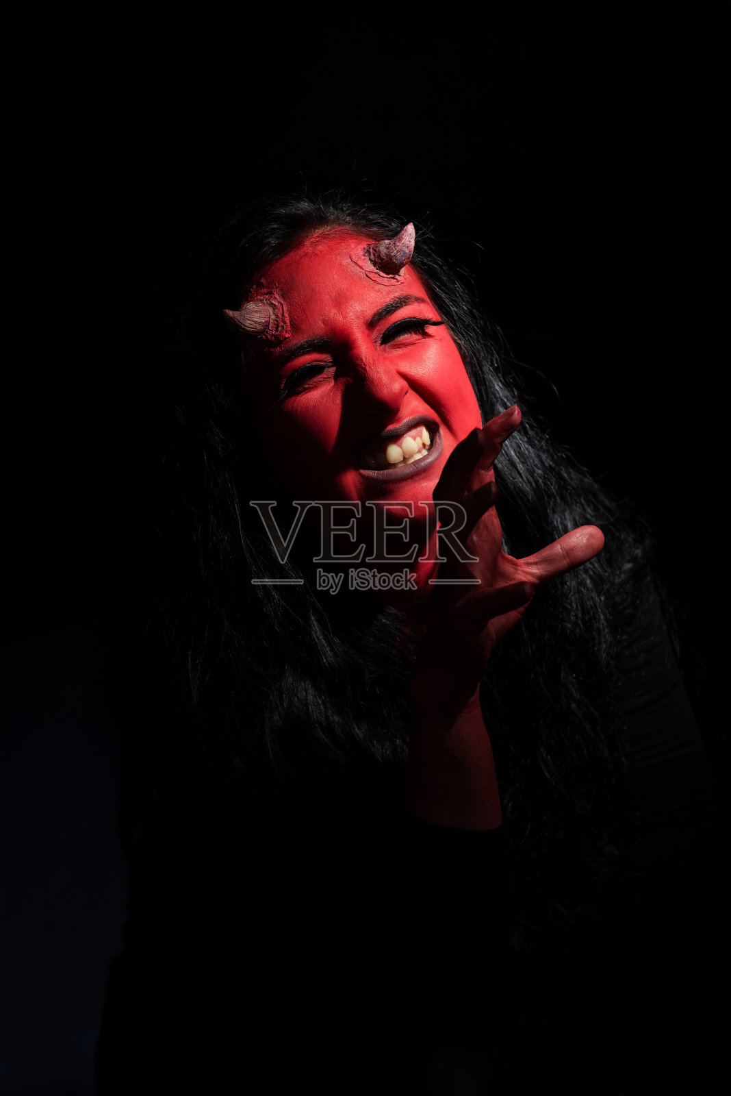 万圣节的概念。恶魔女人与红色的脸和小角在黑色的背景与拷贝空间。照片摄影图片