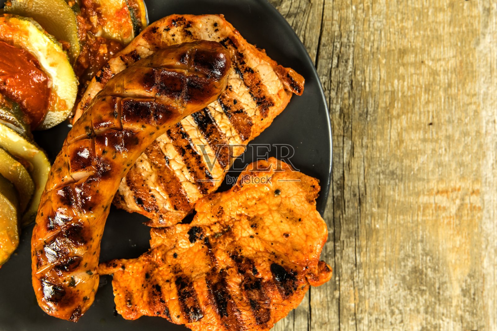 烤香肠和猪排。木制背景。烤的肉。不健康的脂肪类食物。照片摄影图片