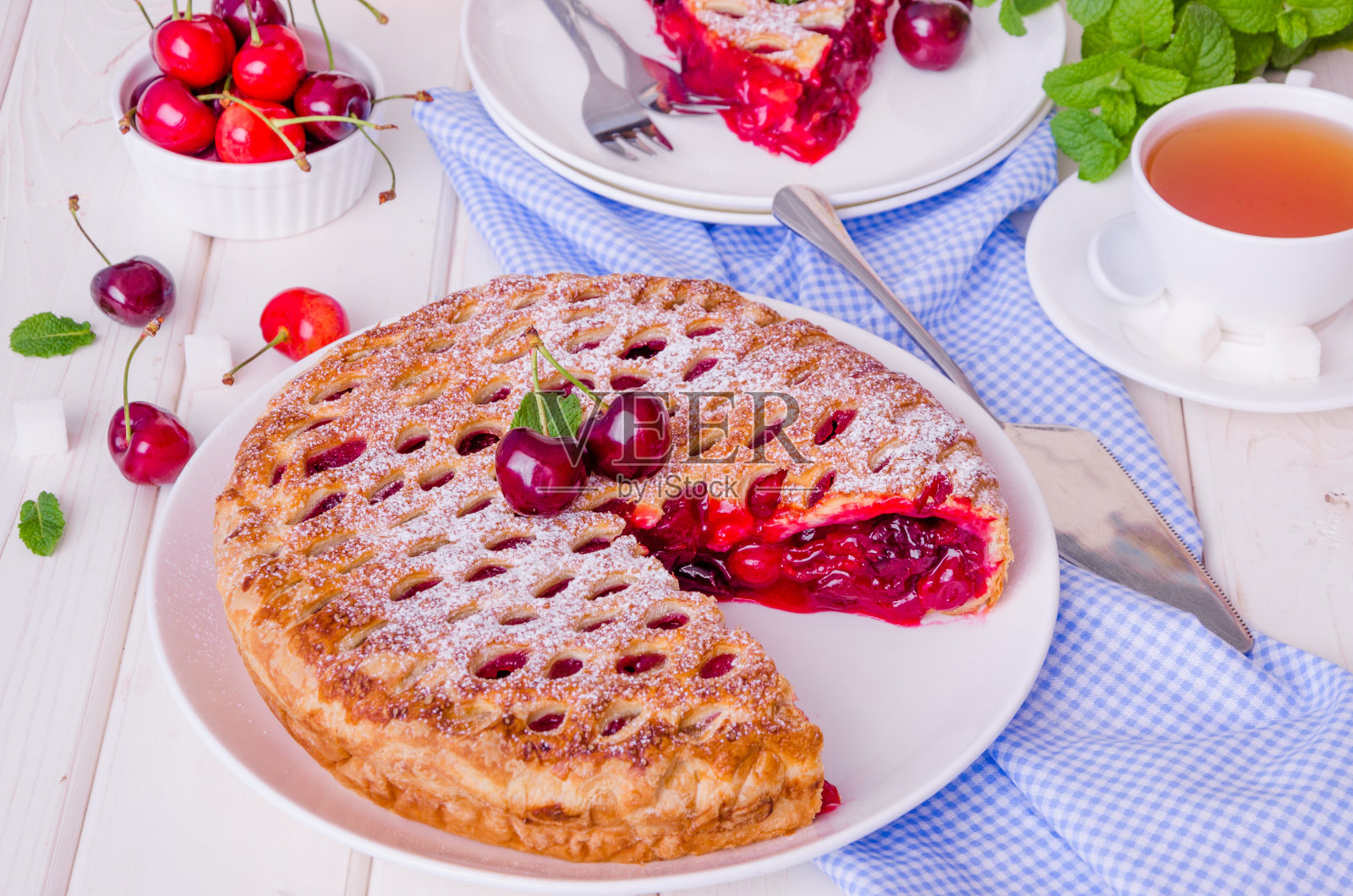 封闭的酥皮蛋糕，白色的木制背景上有樱桃馅。照片摄影图片