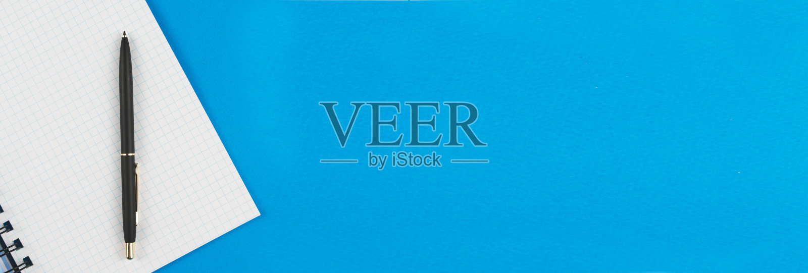 一个蓝色背景的钢笔笔记本。照片摄影图片