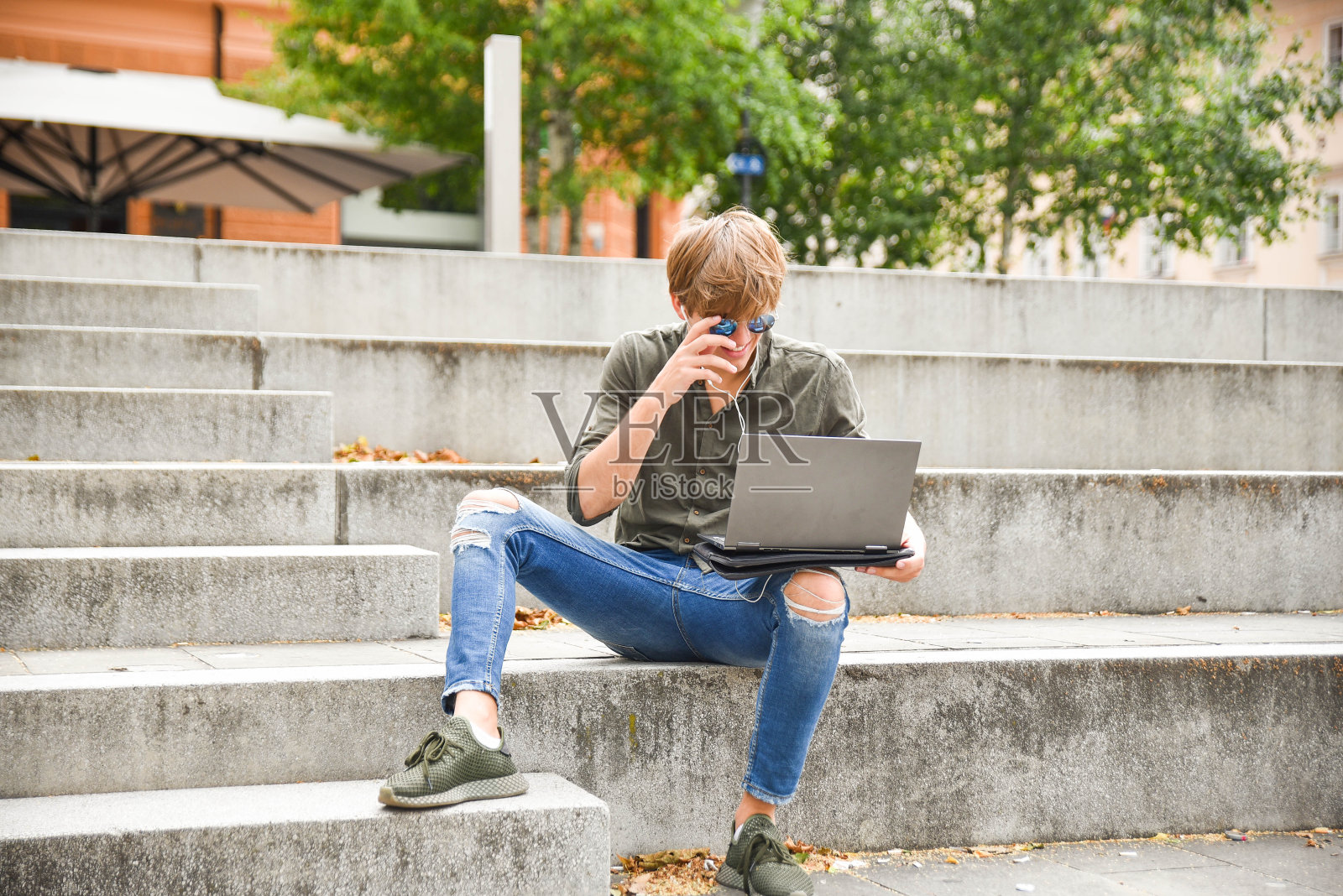 年轻人坐在楼梯上，用着笔记本电脑和耳机照片摄影图片