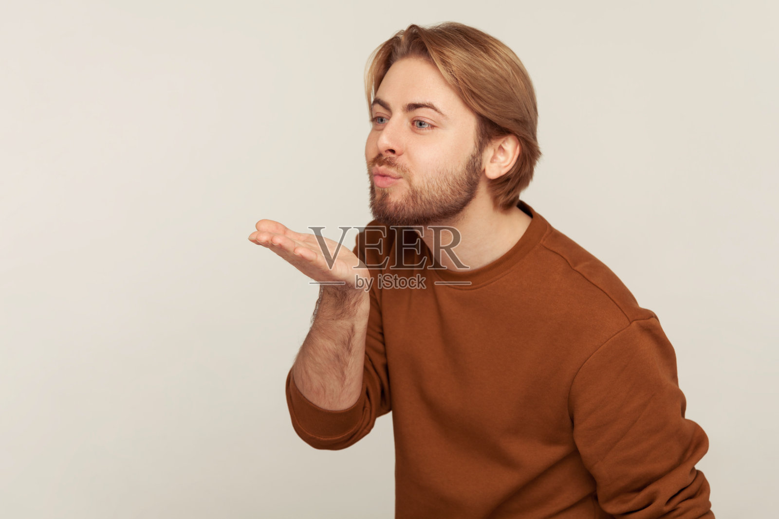 爱你,亲爱的!肖像帅气的男人，头发和胡子整齐穿着运动衫，送浪漫的飞吻照片摄影图片