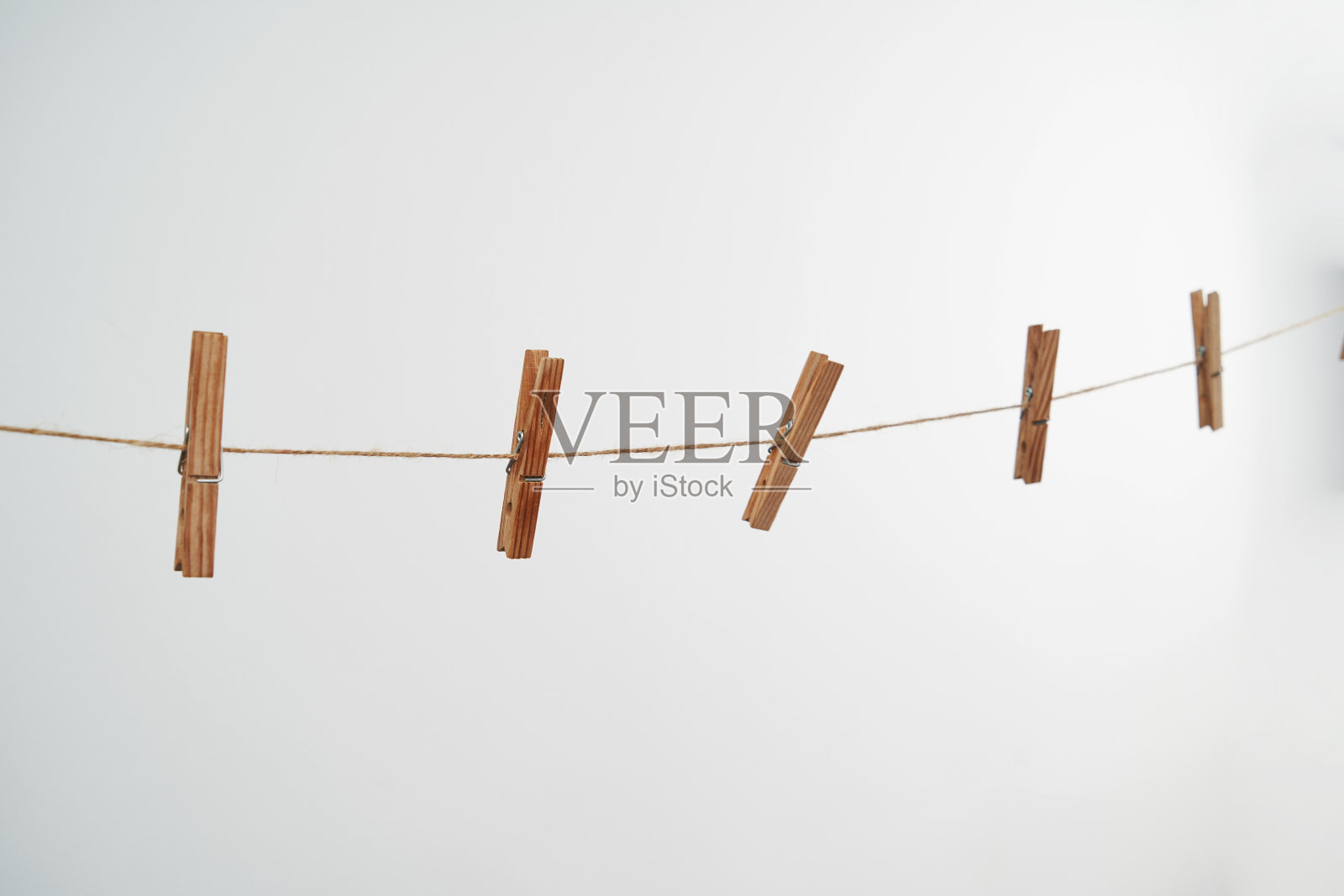 白色背景上的绳子上的木制晾衣夹。照片摄影图片