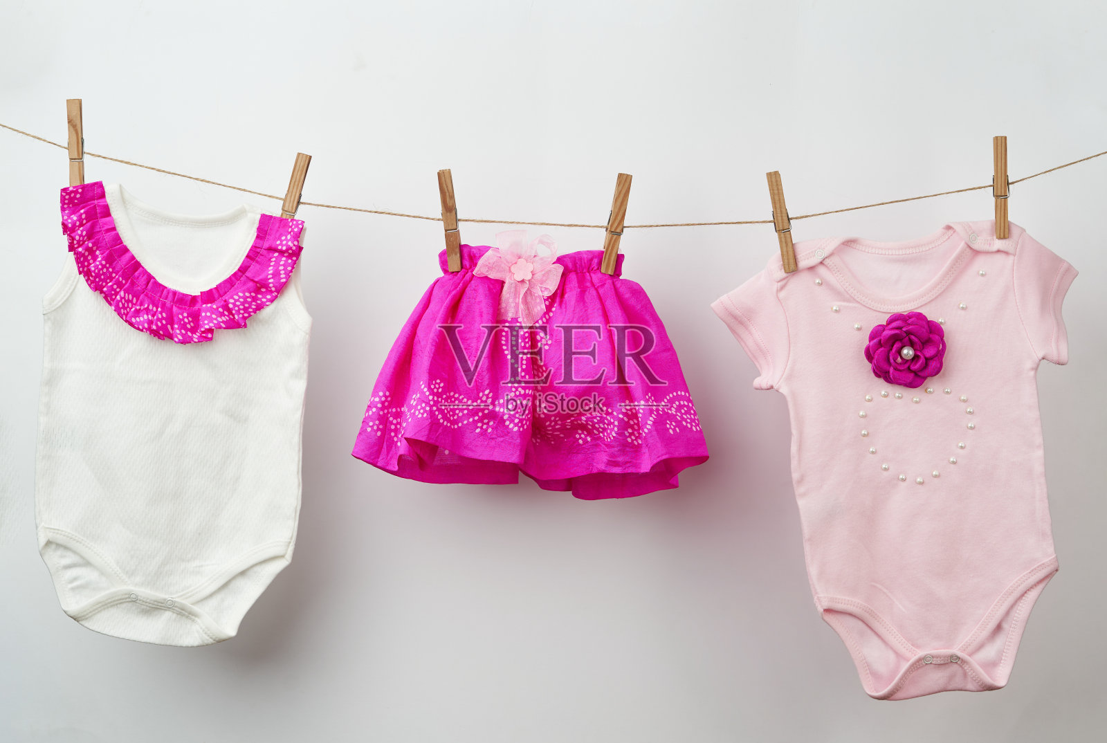 白色背景上的绳子上挂着婴儿衣服照片摄影图片