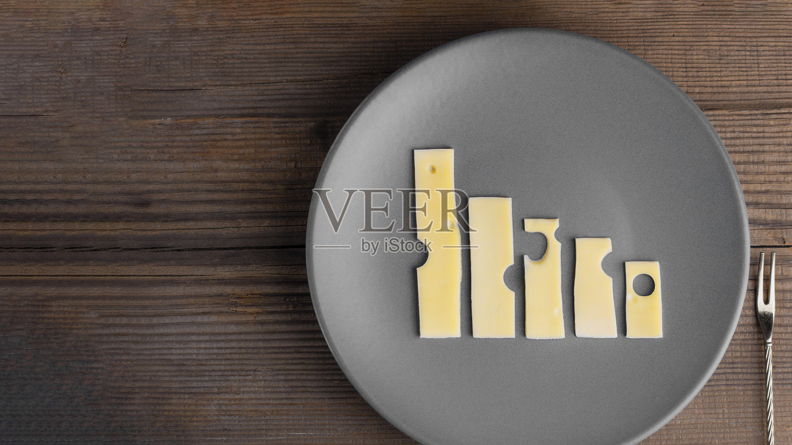 商业衰退和危机。食品的概念。灰色的盘子上放着奶酪图，旁边放着叉子，放在有拷贝空间的木桌上。农业和乳品制造业。俯视图照片摄影图片