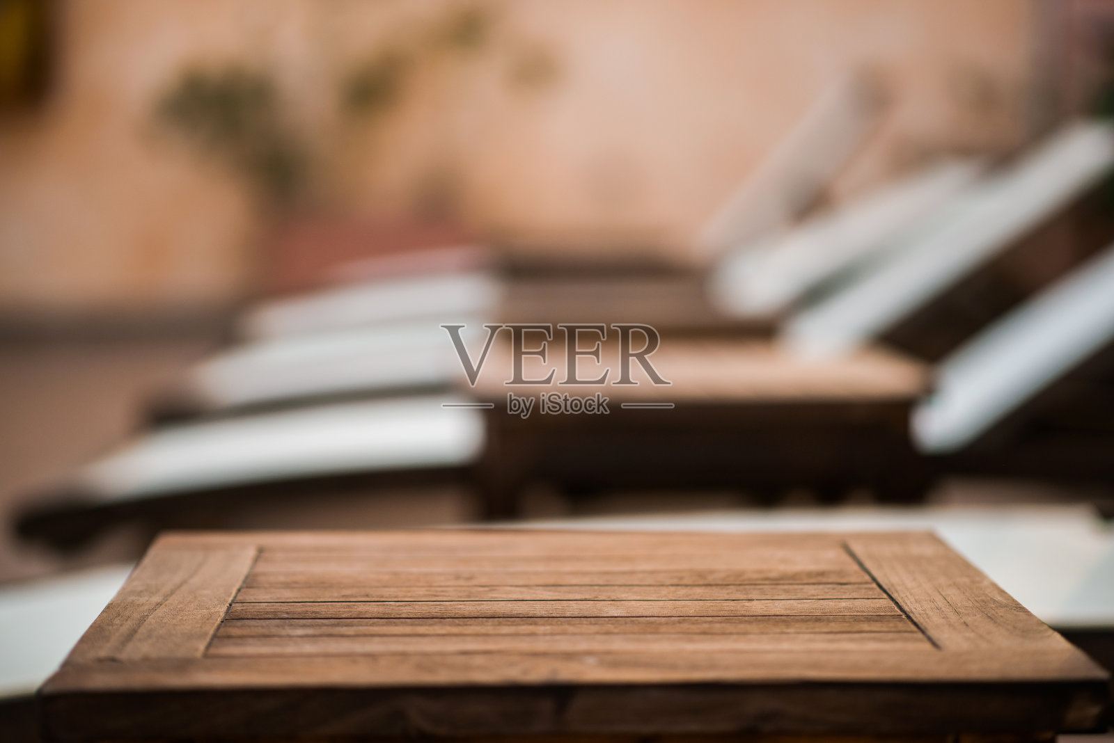 木制桌子的顶部。模糊的背景与日光浴床。照片摄影图片