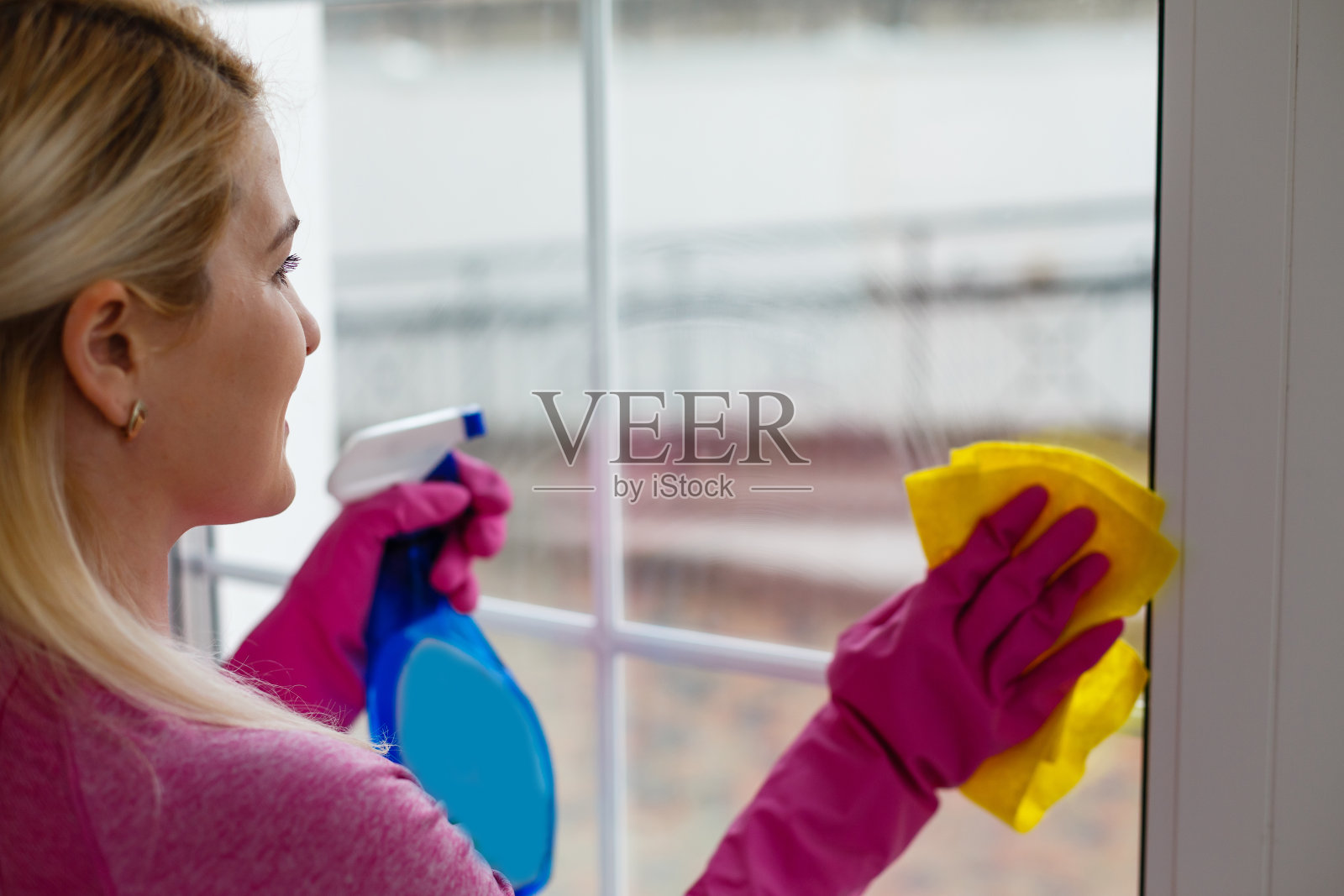 一个女人正在用黄色的布擦窗户照片摄影图片