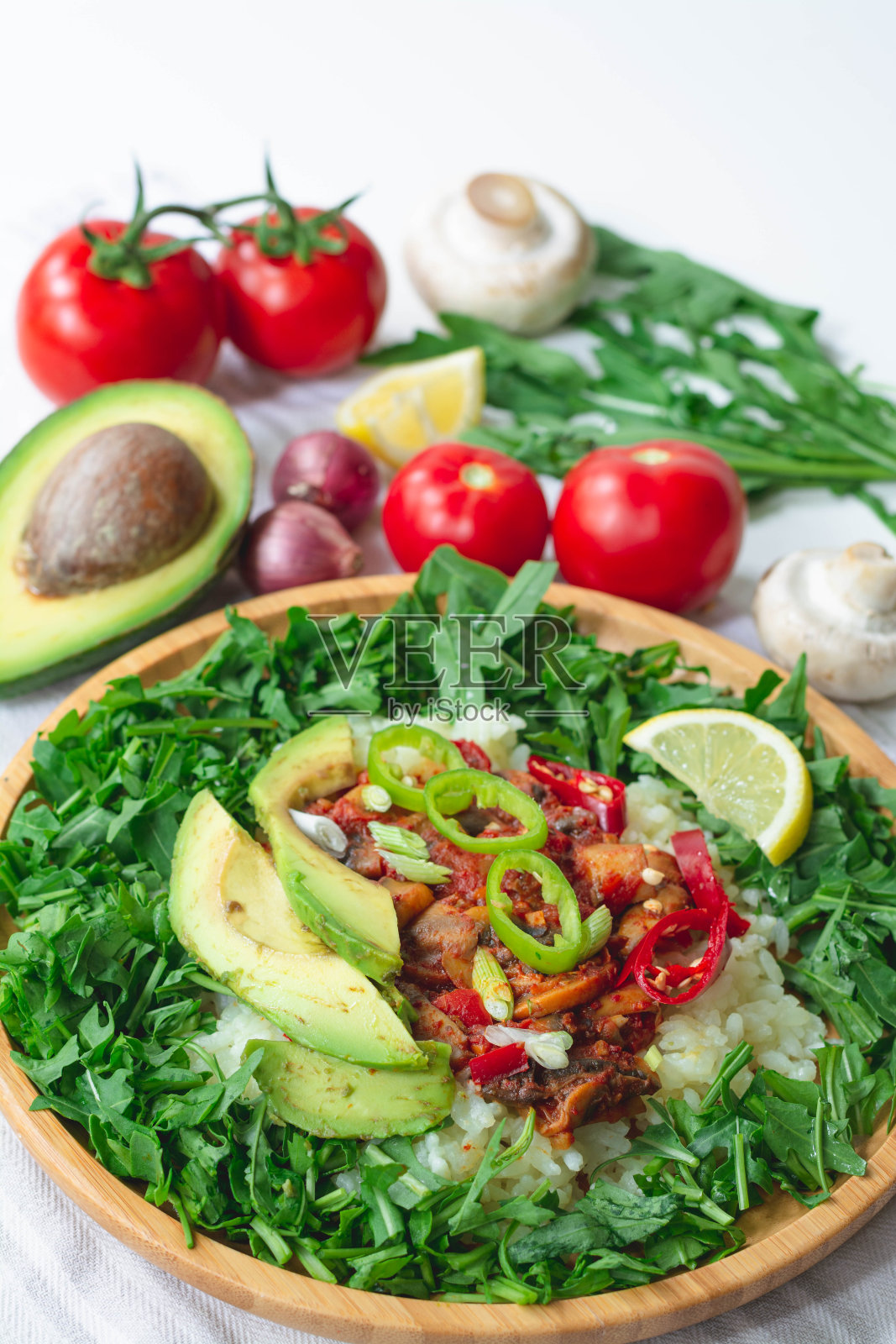 健康时尚的素食玉米煎饼碗，配有白米饭，辣番茄蘑菇混合，绿色芝麻菜，柠檬和鳄梨片。上面撒上红、绿辣椒和青葱照片摄影图片